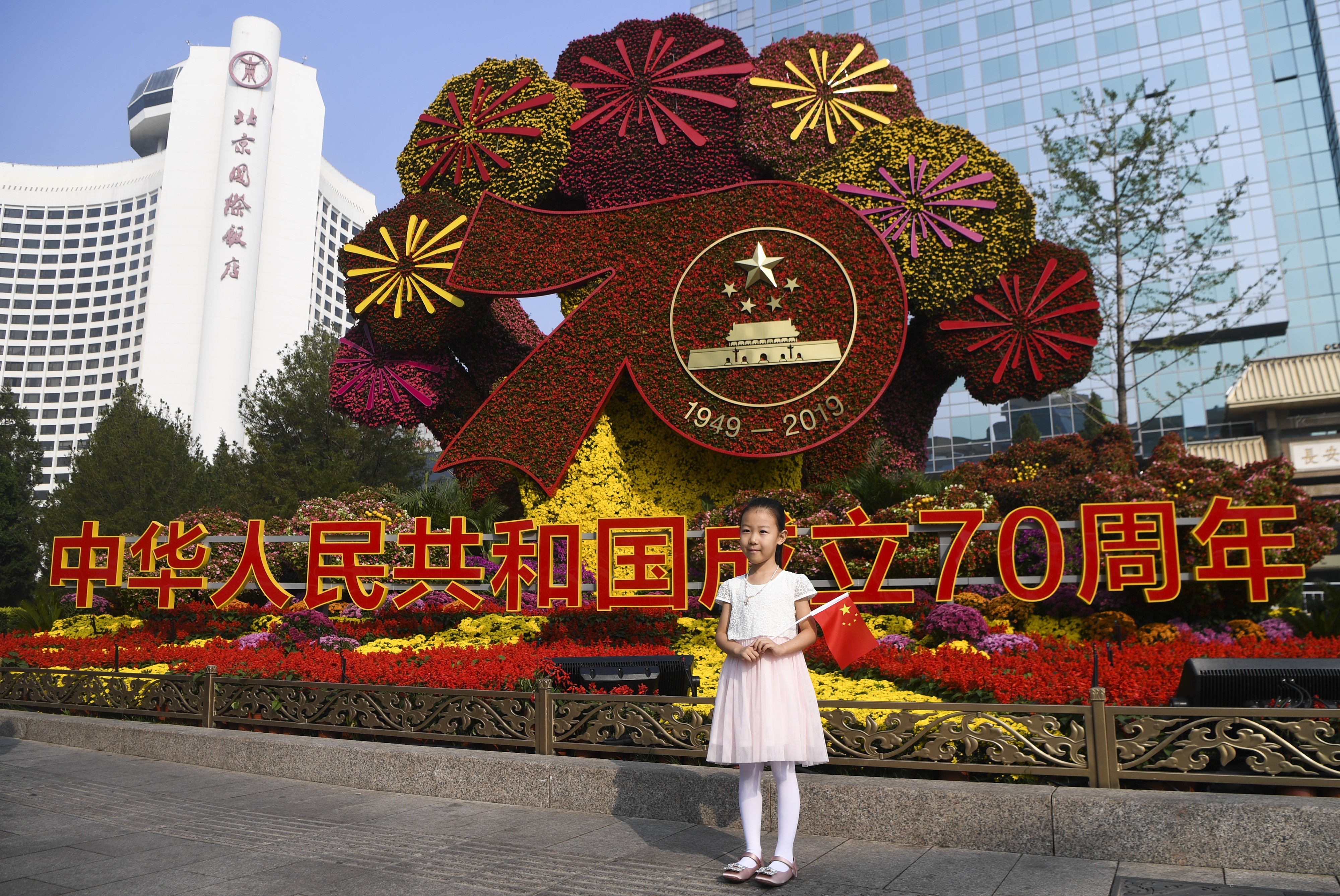 A girl poses for a photo in front of a flower bed in Beijing. Photo: Xinhua