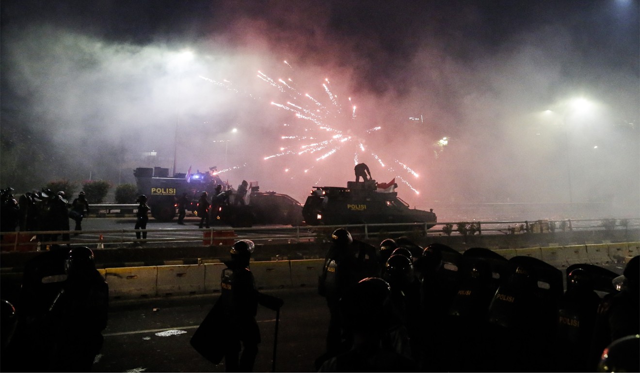 Firecrackers explode over the heads of riot police. Photo: EPA