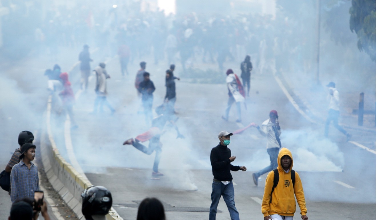 Students stand in tear gas fired by Indonesian police outside the parliament compound. Photo: EPA