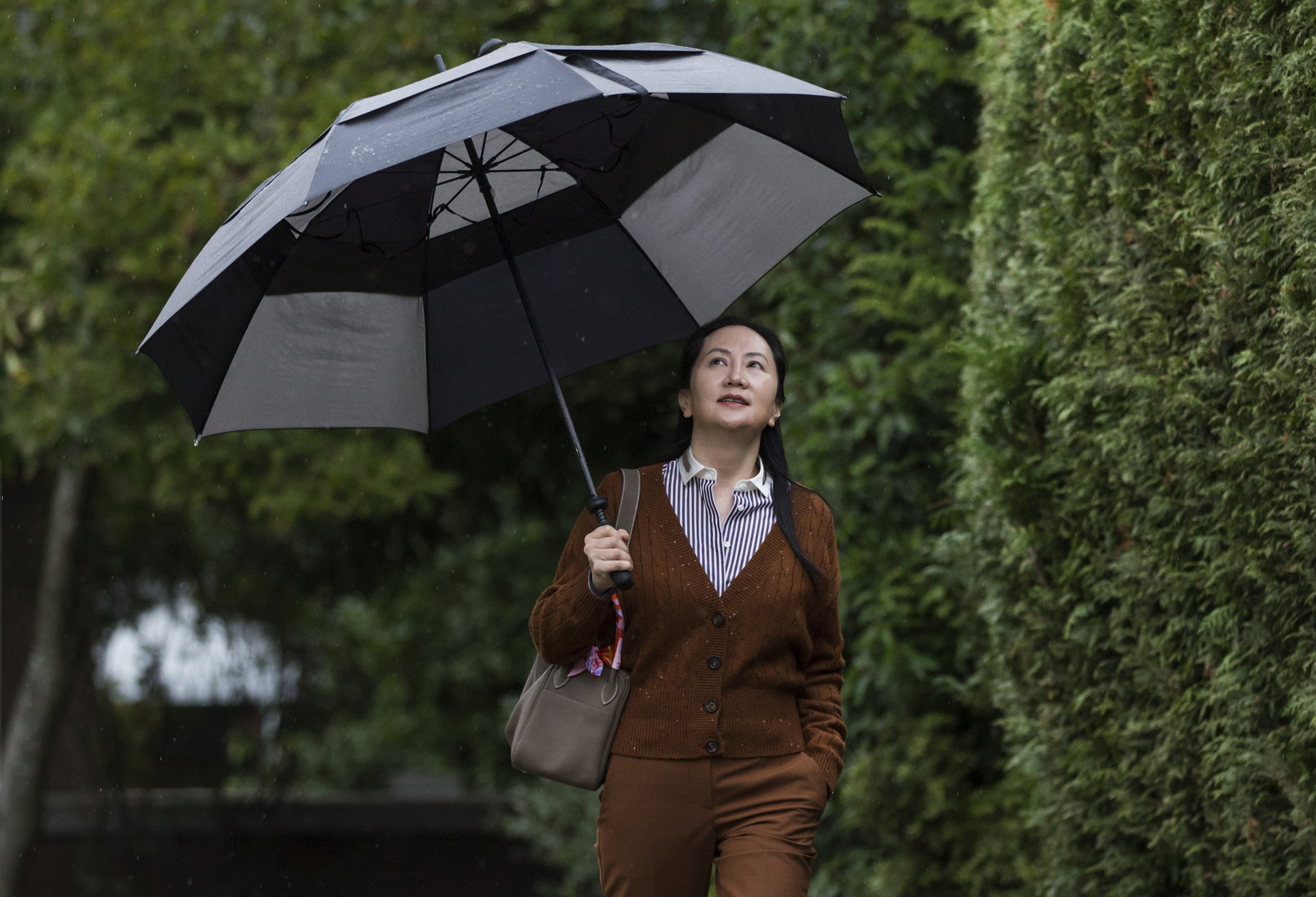 Huawei chief financial officer Meng Wanzhou shields herself from rain as she leaves her home to attend a court hearing in Vancouver, British Columbia, on Thursday. Photo: The Canadian Press via AP