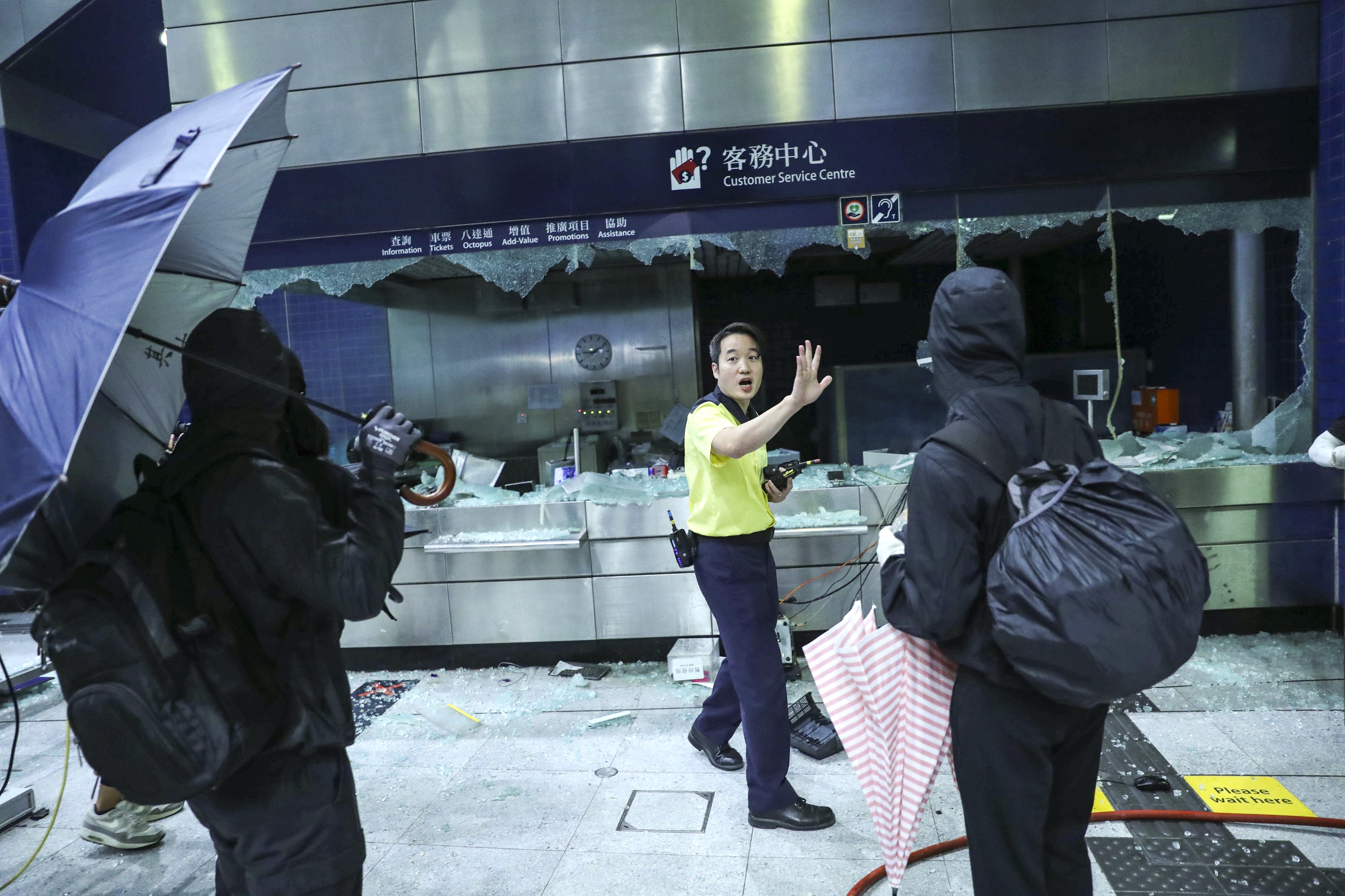 An MTR employee tries to stop masked protesters causing more damage at the already and vandalised Tai Wai station. Photo: Sam Tsang