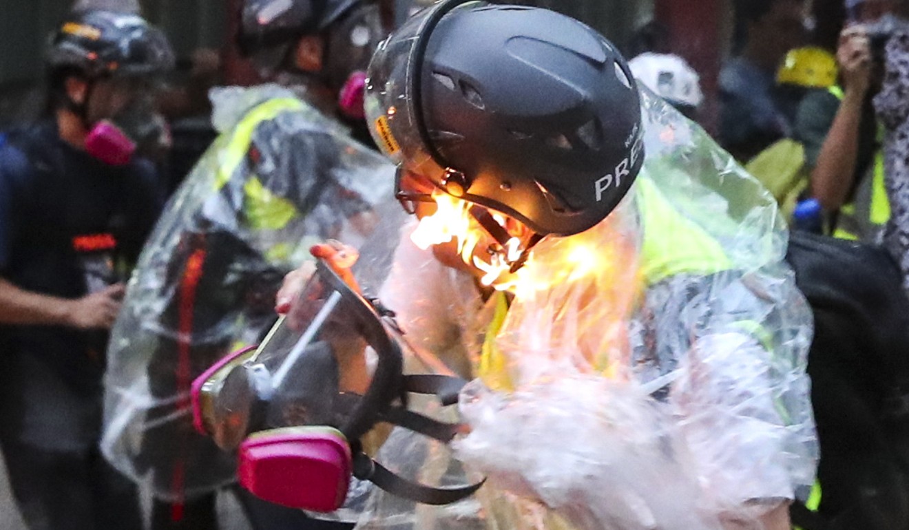 An RTHK journalist is burned after a petrol bomb sets his raincoat on fire. Photo: Sam Tsang