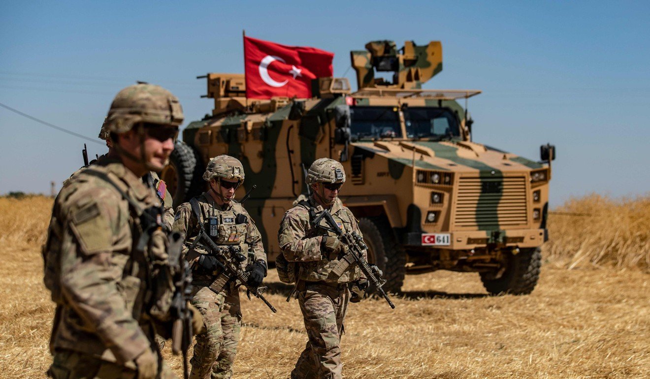 US troops walk past a Turkish military vehicle during a joint patrol with Turkish troops in the Syrian village of al-Hashisha. Photo: AFP