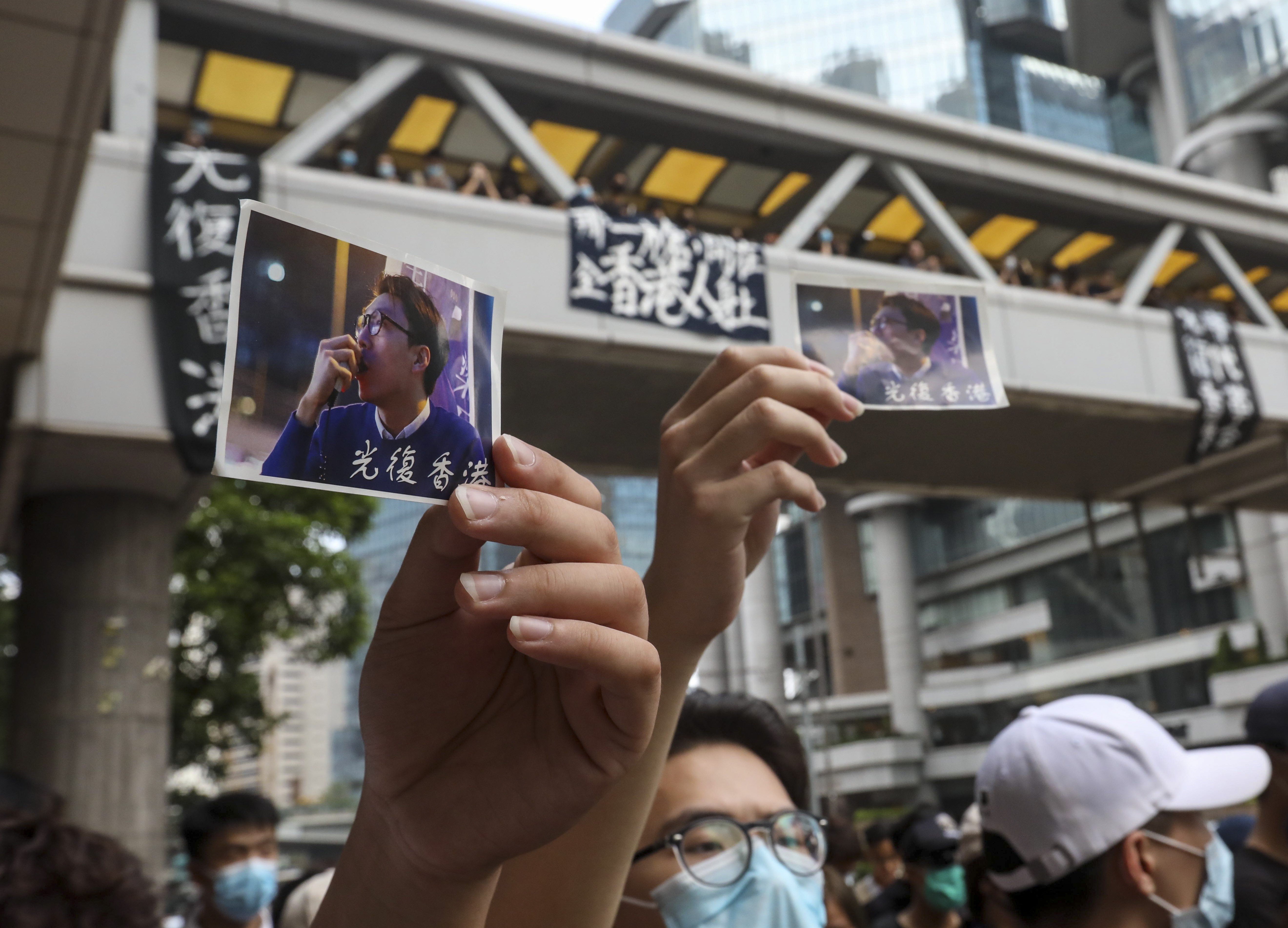 Masked protesters hold photographs of activist Edward Leung, jailed for taking part in the 2016 Mong Kok riots. Photo: Nora Tam