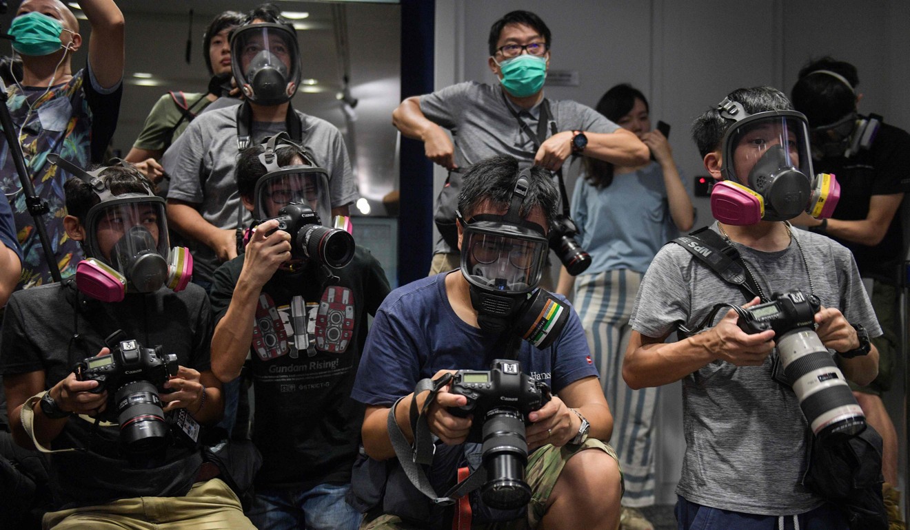 Photojournalists wear gas masks at a police press conference as a protest. Photo: AFP