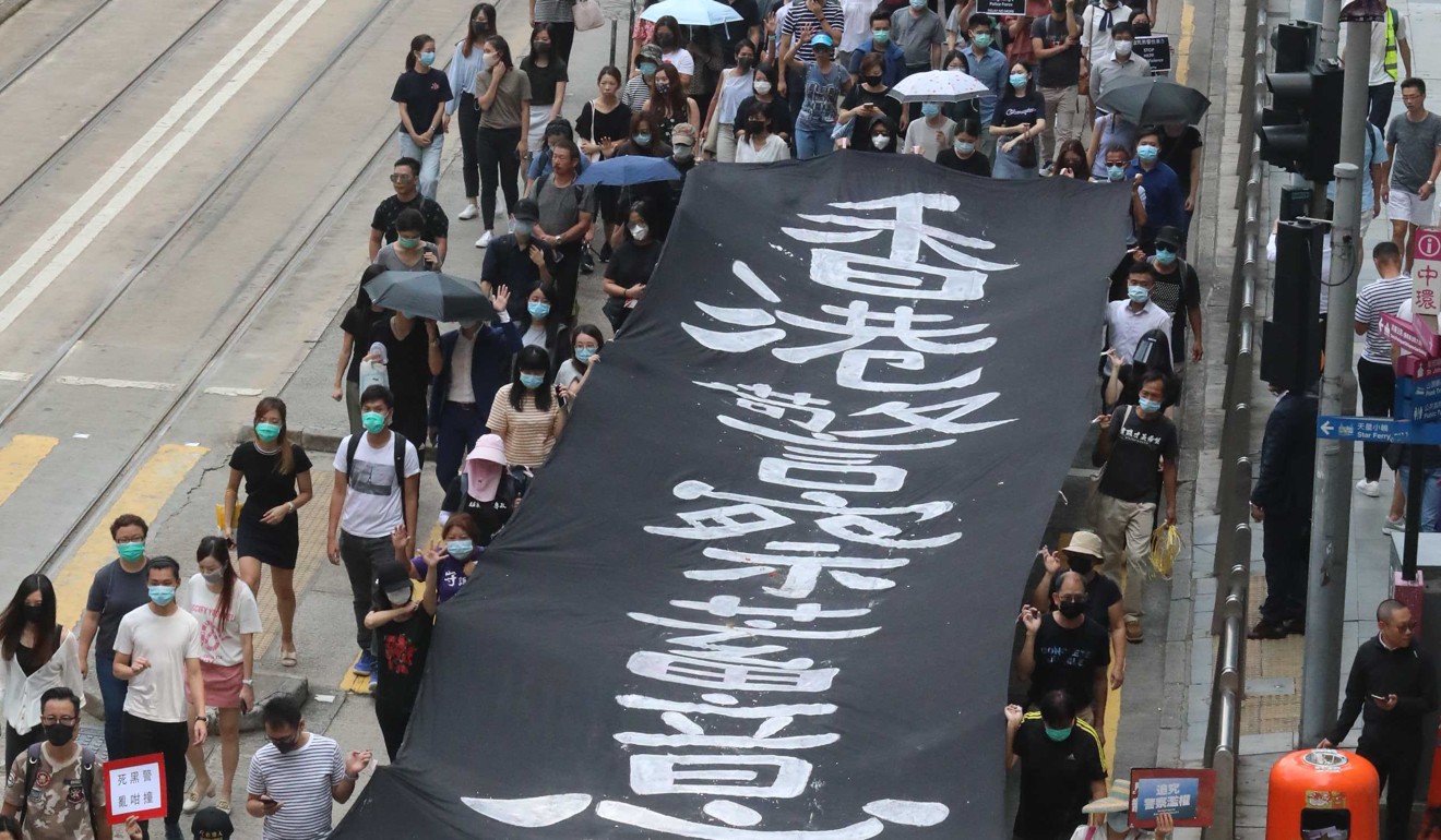 A huge anti-police banner is unfurled and carried by marchers. Photo: Felix Wong