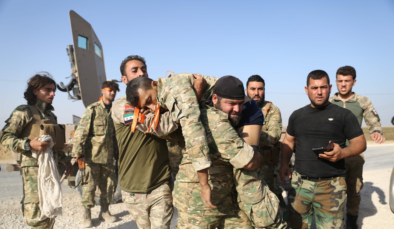 Turkish-backed Syrian fighters evacuate a wounded comrade near the border town of Ras al-Ain. Photo: AFP