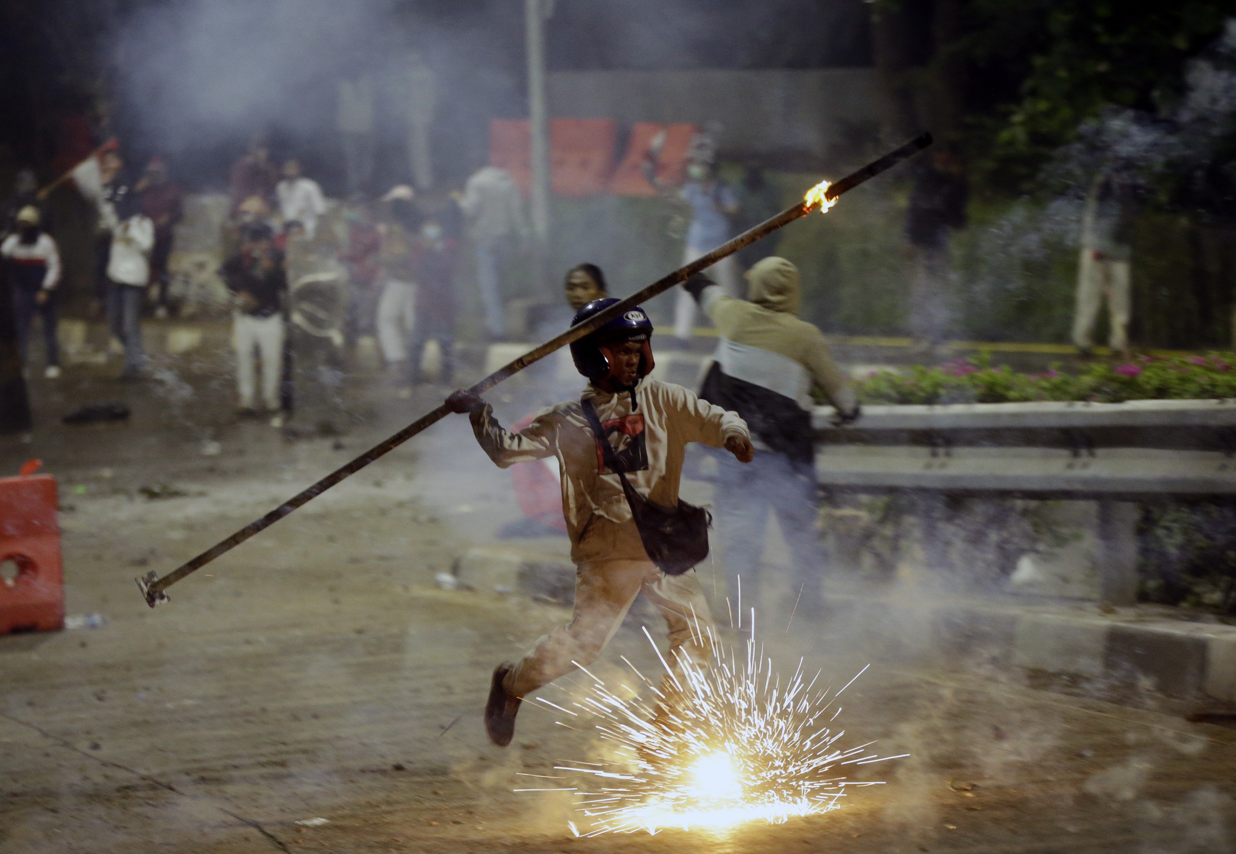 A student protester throws a burning stick at riot police during a clash in Jakarta on September 30. Photo: AP