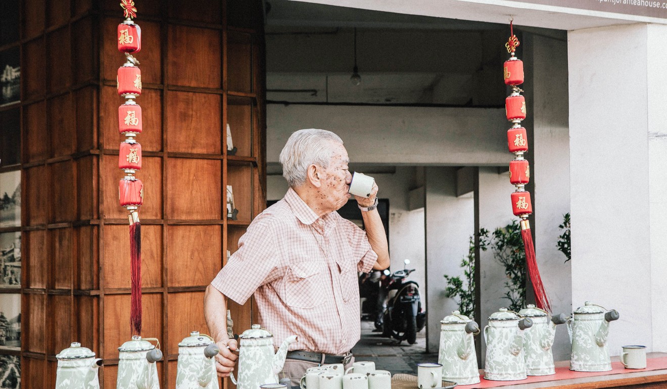 A passer-by drinks a cup of hot tea that is provided free of charge to the public by Pantjoran Tea House. Photo: Agoes Rudianto