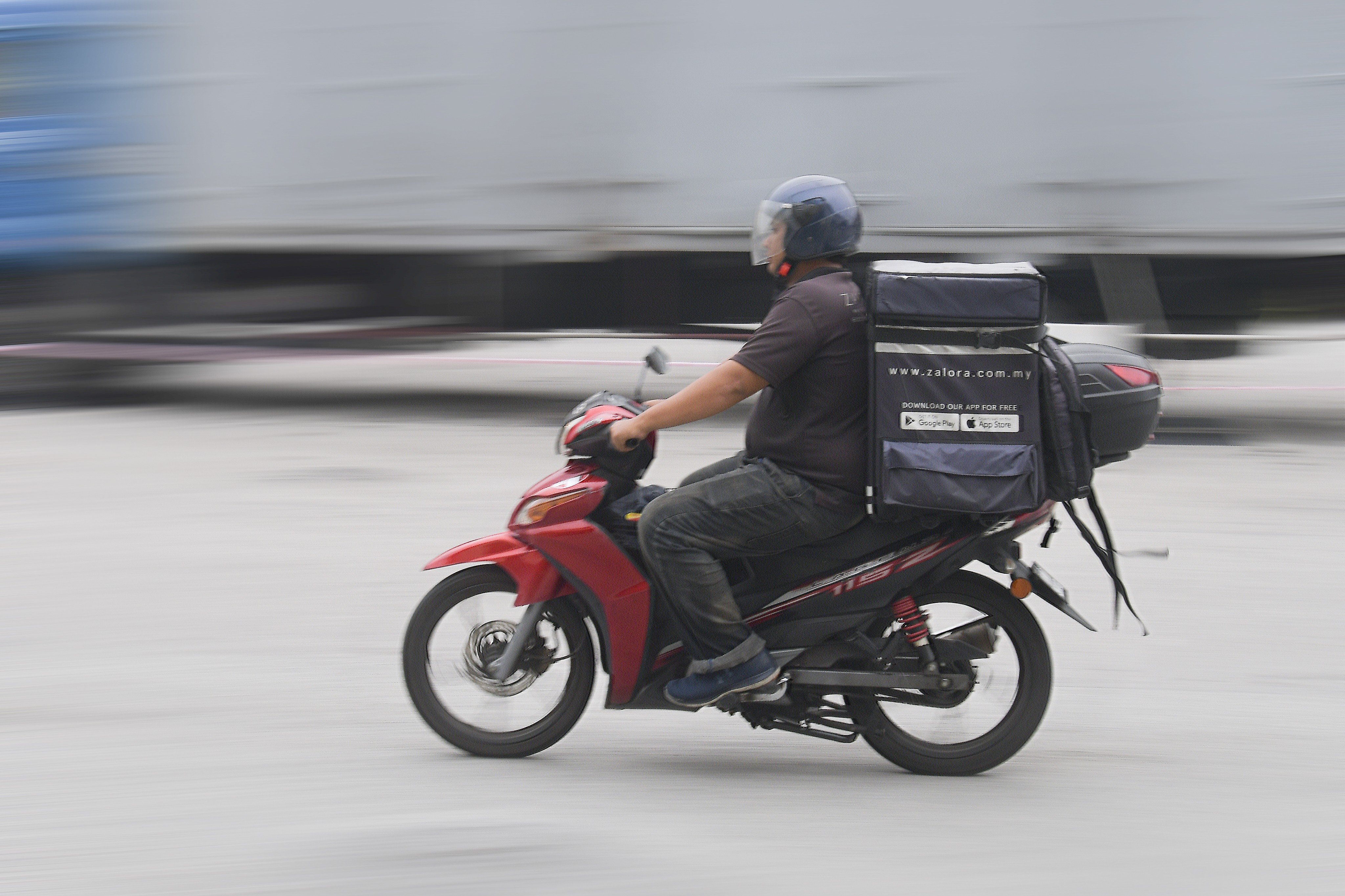 A Zalora courier rider rides his motorcycle in Kuala Lumpur. Photo: Zahim Mohd