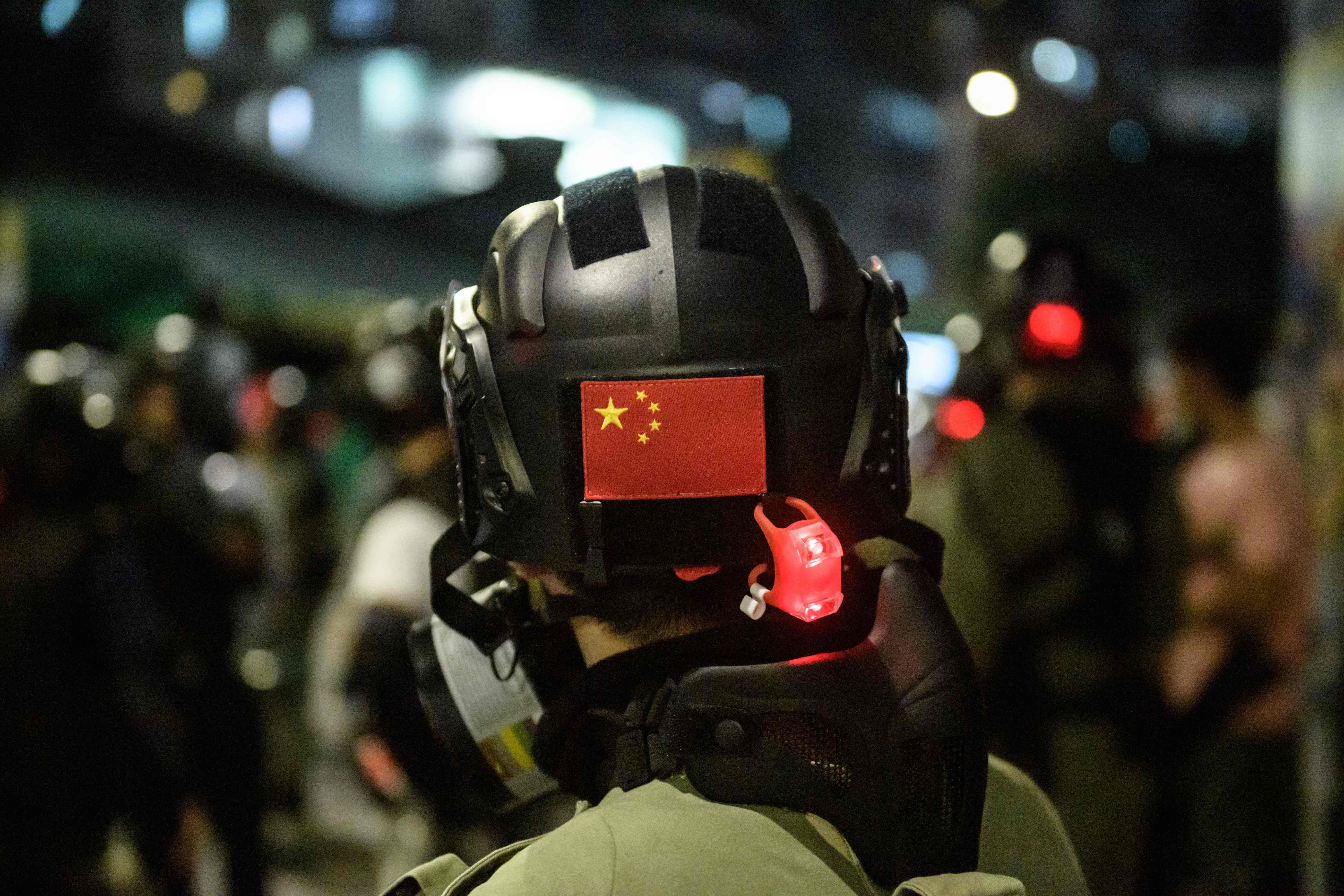 A Chinese flag is displayed on the back of a riot police officer’s helmet in Hong Kong on October 21. Beijing is unlikely to concede greater democratic freedoms in Hong Kong without at least the safeguard of a law against sedition and subversion. Photo: AFP