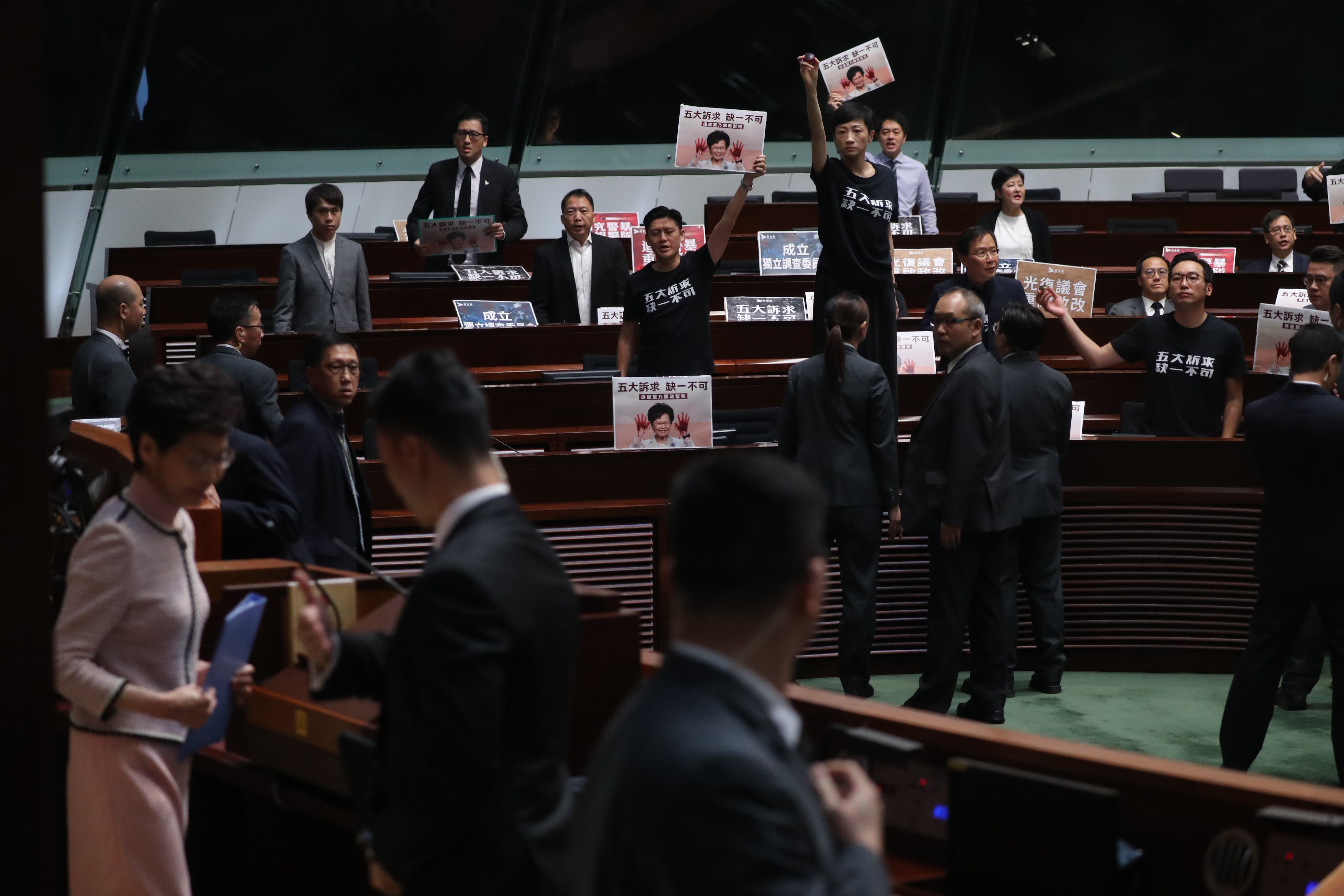 Tanya Chan stands on a table as opposition lawmakers hold up protest posters and disrupt Chief Executive Carrie Lam’s policy address, in the Legislative Council chamber on October 16. Photo: Edward Wong