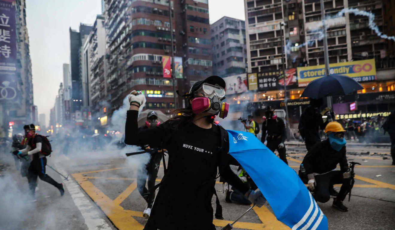 A Hong Kong protester throws back a tear-gas canister fired by police in the Mong Kok district. The unrest has been ongoing for more than four months. Photo: AFP