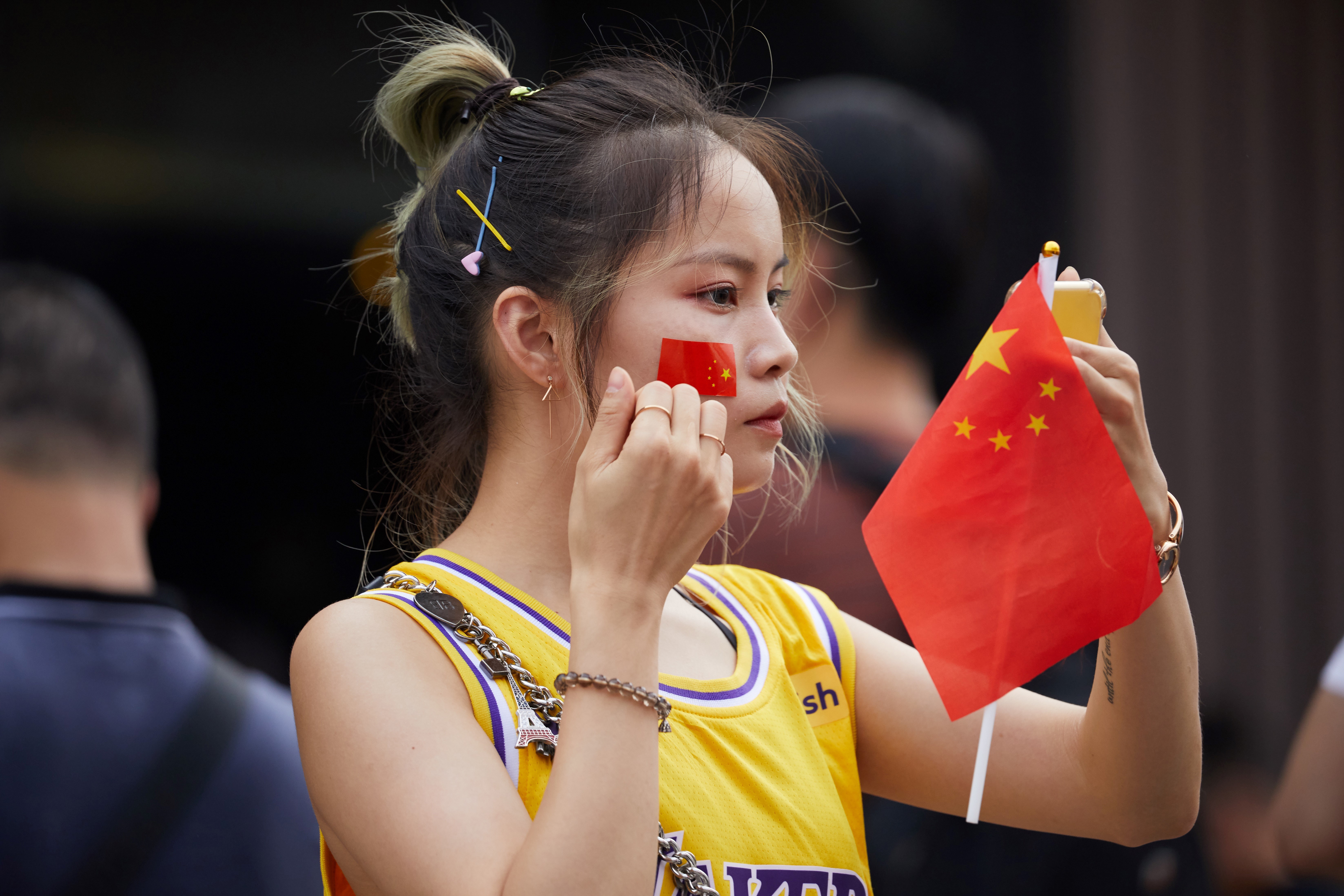 A Los Angeles Lakers fan puts on a Chinese flag sticker before attending an NBA preseason game between the Los Angeles Lakers and the Brooklyn Nets in Shenzhen on October 12. Photo: AFP