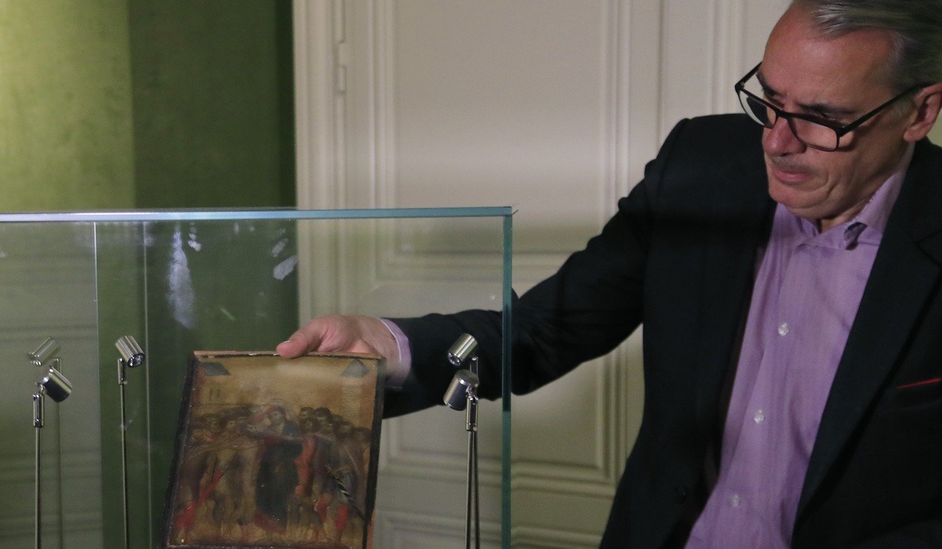 Stephane Pinta takes takes a painting by Italian master Cimabue out of a glass case in Paris in September. Photo: AP