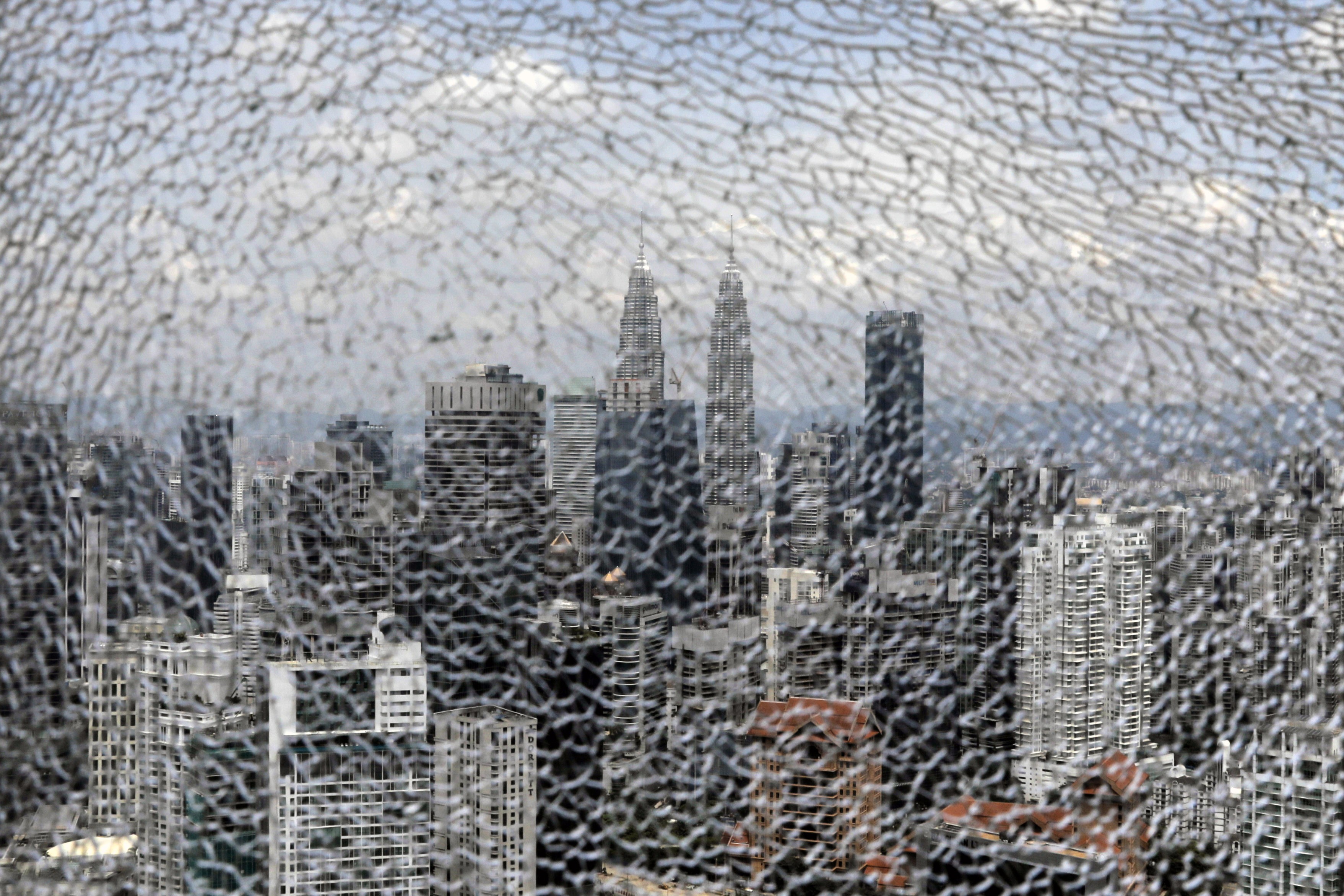 The Petronas Twin Towers are seen in the distance through a shattered glass pane inside The Exchange 106 tower at the Tun Razak Exchange financial district in Kuala Lumpur, Malaysia, on October 23. Malaysia’s latest budget offers manufacturers incentives to relocate their plants to the country. Photographer: Bloomberg