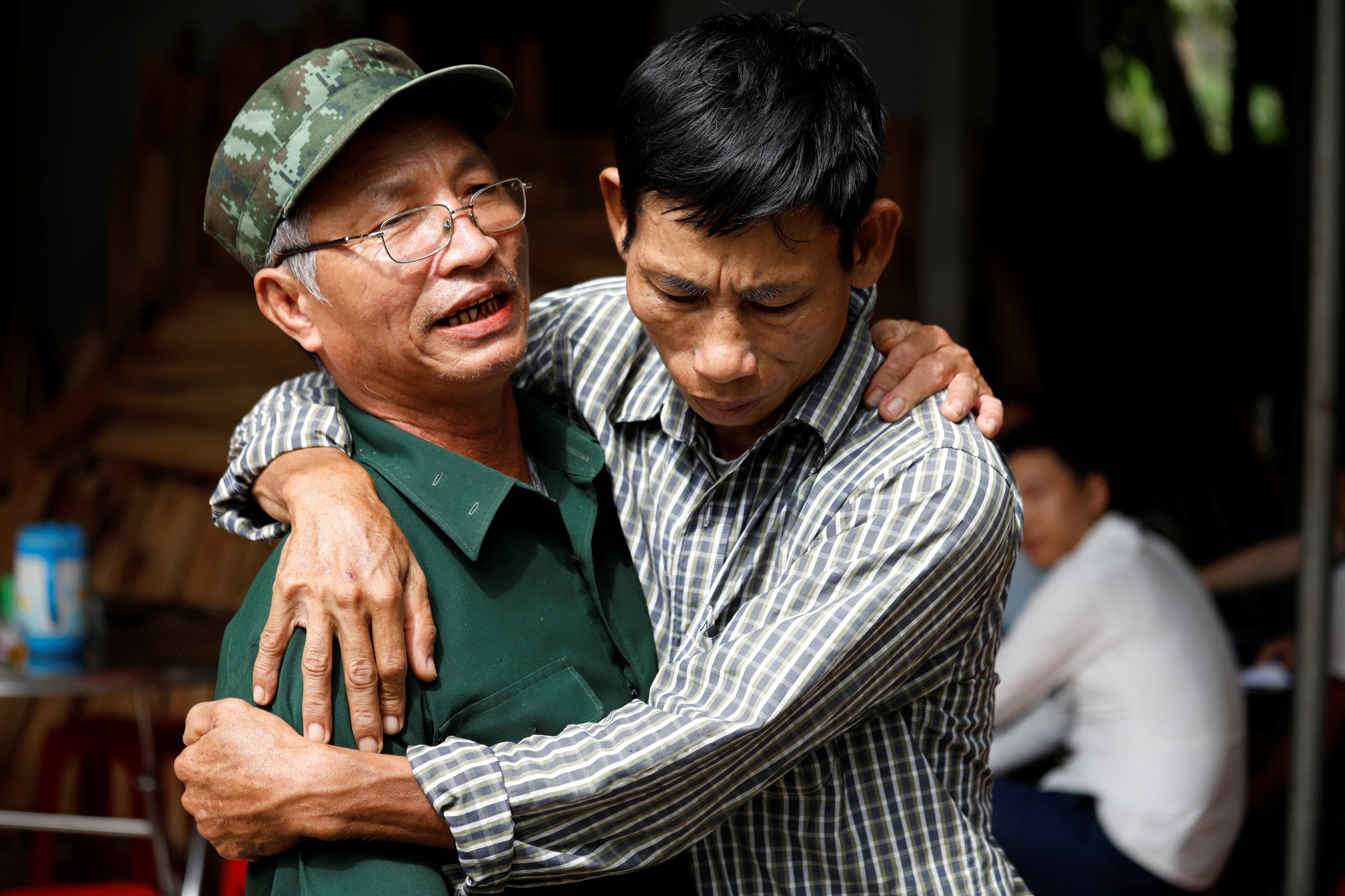 Nguyen Dinh Gia (right), father of Nguyen Dinh Luong, one of the suspected truck death victims, is embraced by a friend at his home in Ha Tinh province, Vietnam, on Sunday. Photo: Reuters