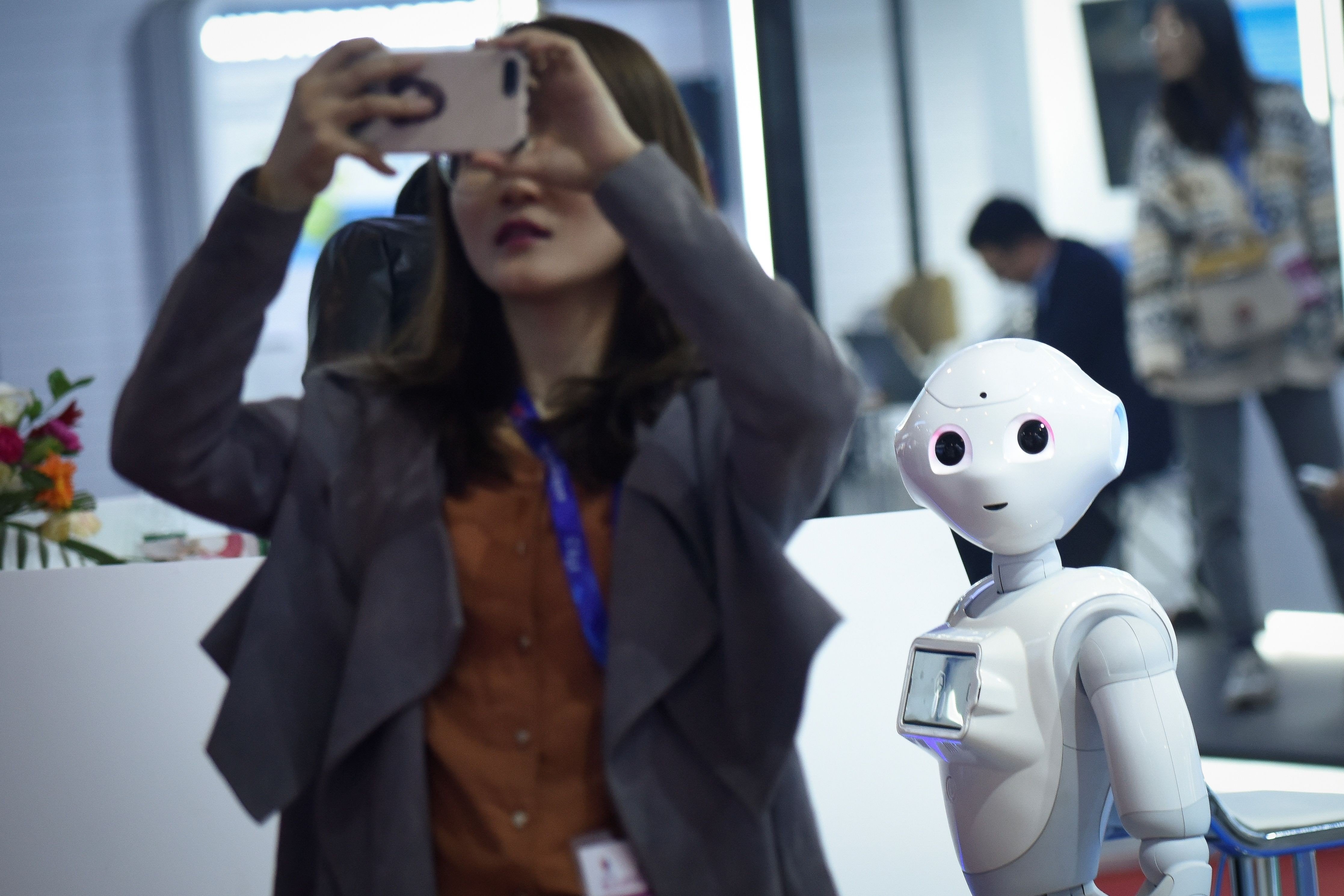 A robot watches a woman using her mobile phone at China Beijing International High-Tech Expo in Beijing on October 24. Photo: AFP