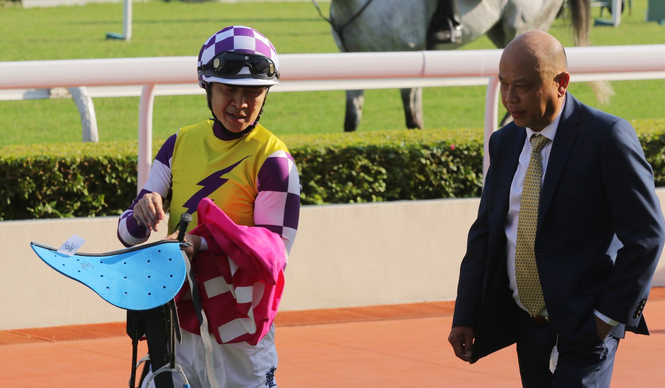 Trainer Joe Lau discusses the race with jockey Peter Ho at Sha Tin on Sunday.