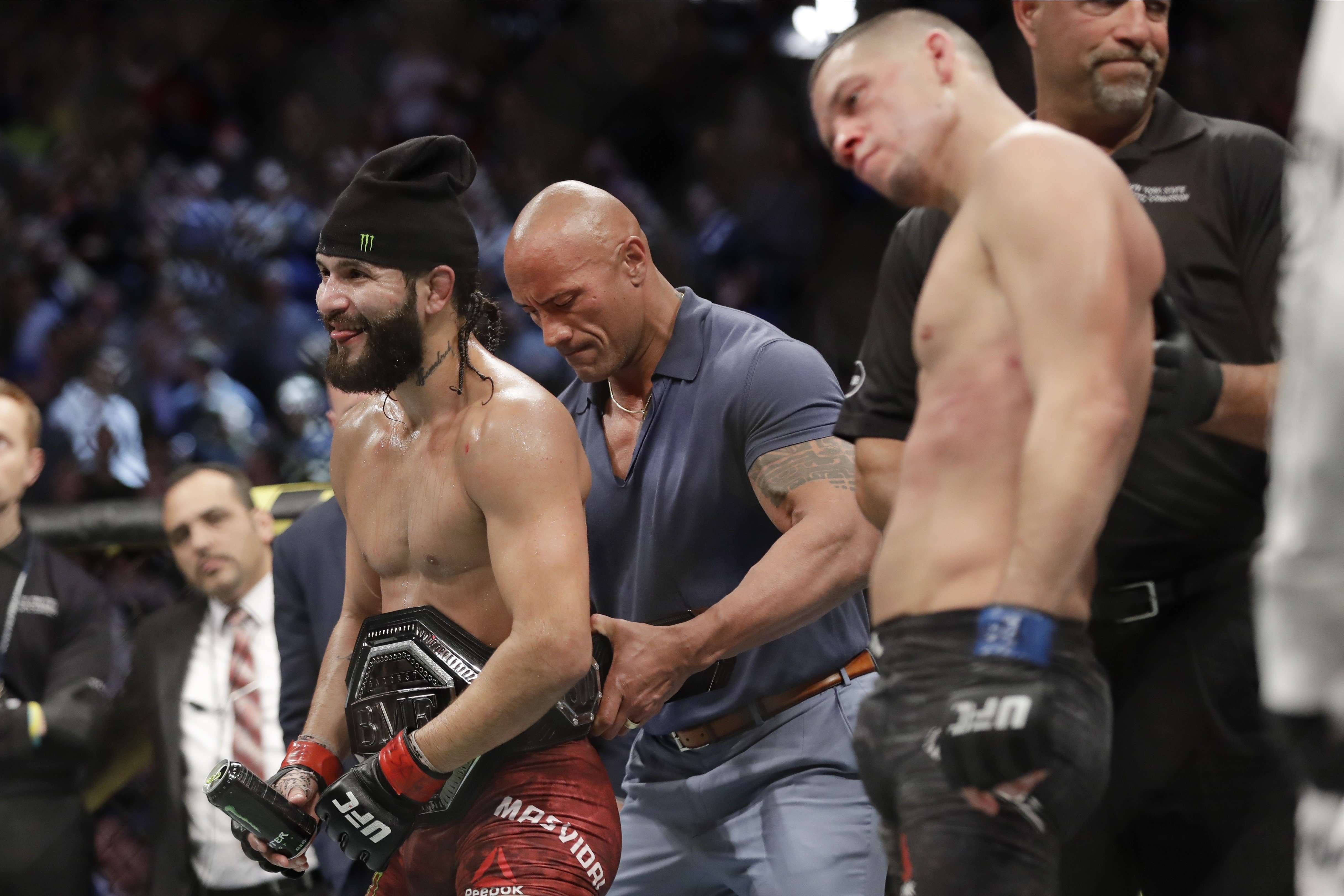 Dwayne ‘The Rock’ Johnson places the ‘BMF’ belt on Jorge Masvidal as Nate Diaz looks dejected. Photo: AP