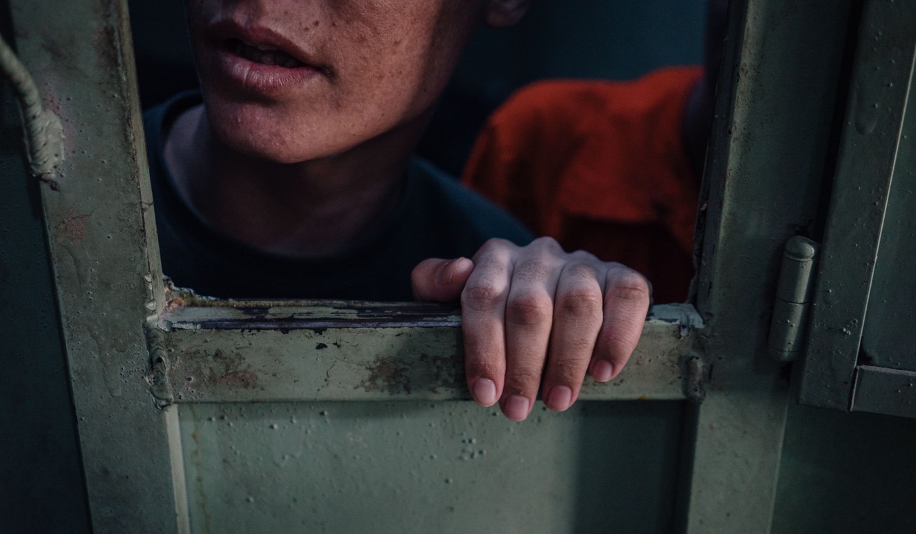 A 14-year-old boy peeks out of a cell. Photo: Alice Martins for The Washington Post