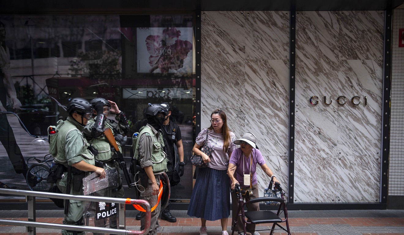 Pedestrians walk past riot police in front of a Gucci store during a protest in Causeway Bay, Hong Kong, on September 29. The trade war and the ongoing anti-government protests in Hong Kong have taken a toll on the city’s economy. Photo: Bloomberg