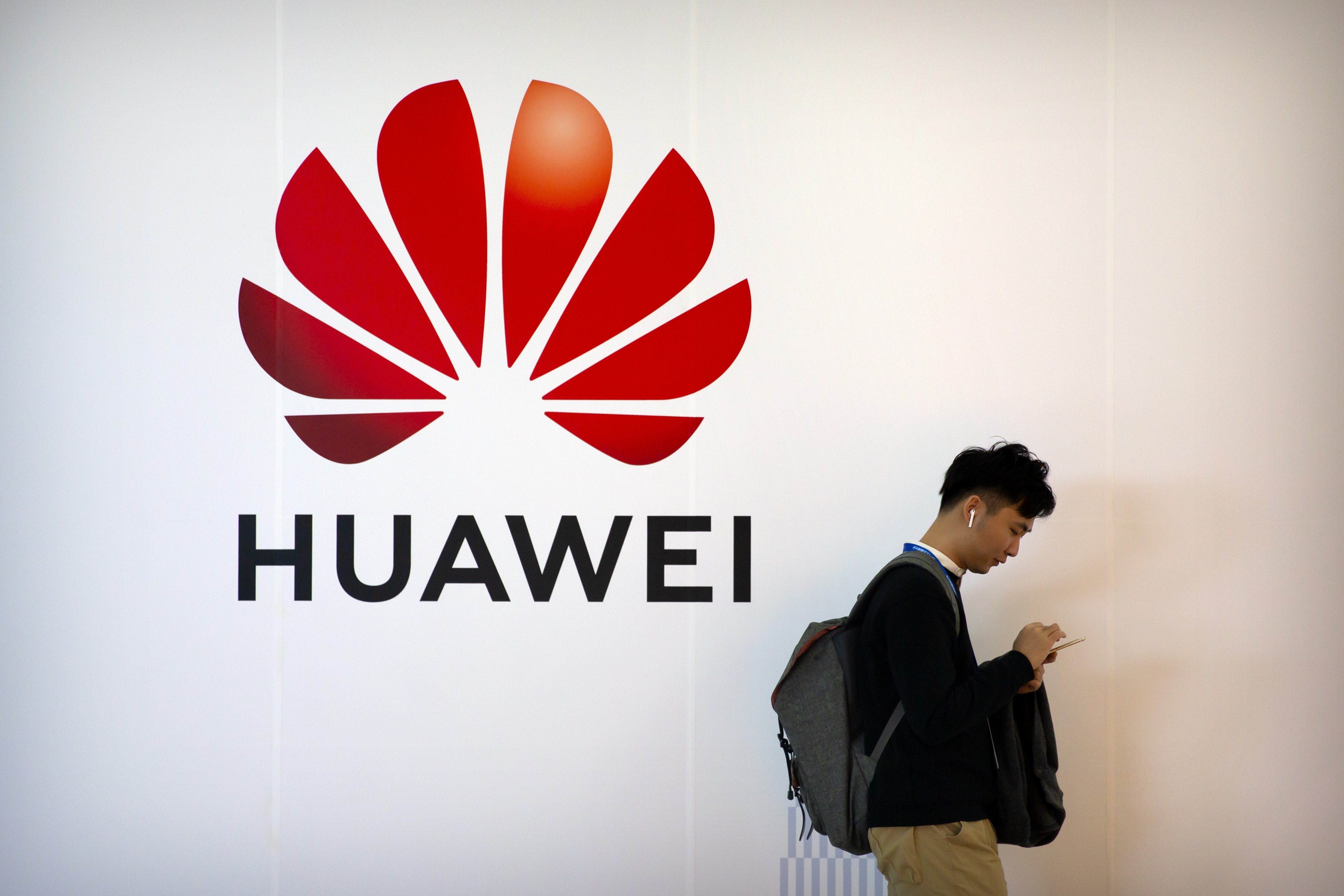 A man uses his smartphone as he stands near a billboard for Chinese technology firm Huawei at the PT Expo in Beijing, Thursday, Oct. 31, 2019. Photo: AP.