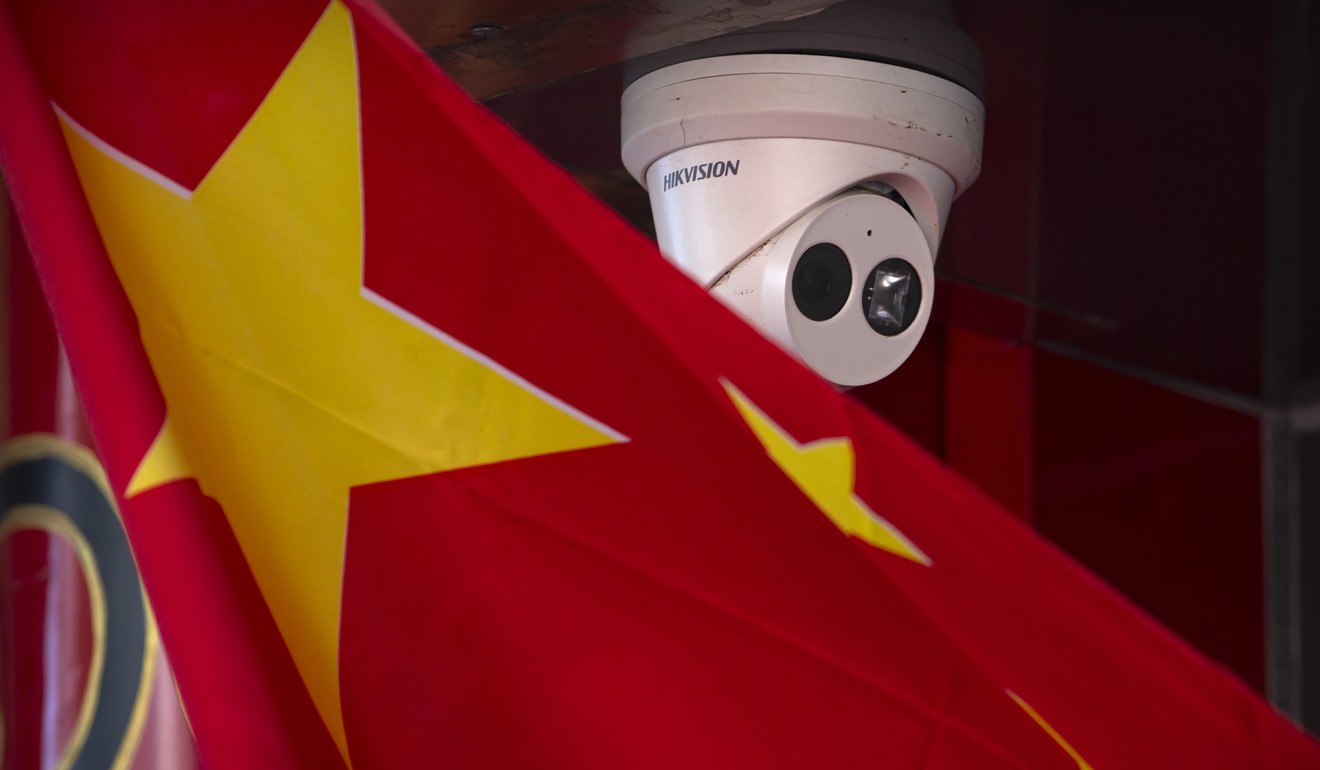A Chinese flag hangs near a Hikvision security camera outside a Beijing shop. Photo: AP