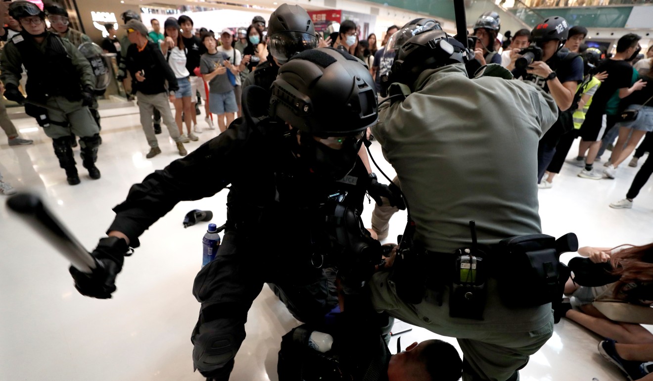 Police officers hit a man as shoppers and anti-government protesters gather in Sha Tin, Hong Kong, on Sunday. Photo: Reuters