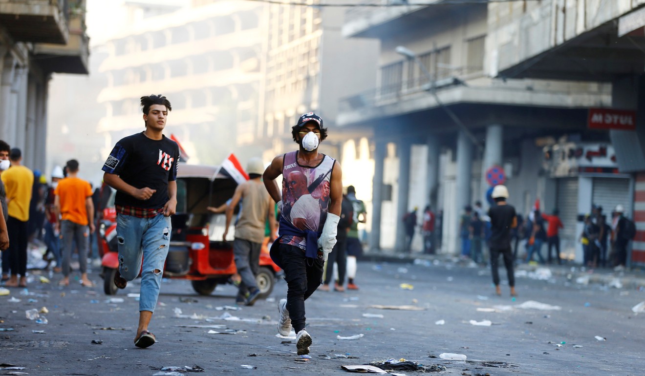 Demonstrators run during the ongoing anti-government protests in Baghdad. Photo: Reuters