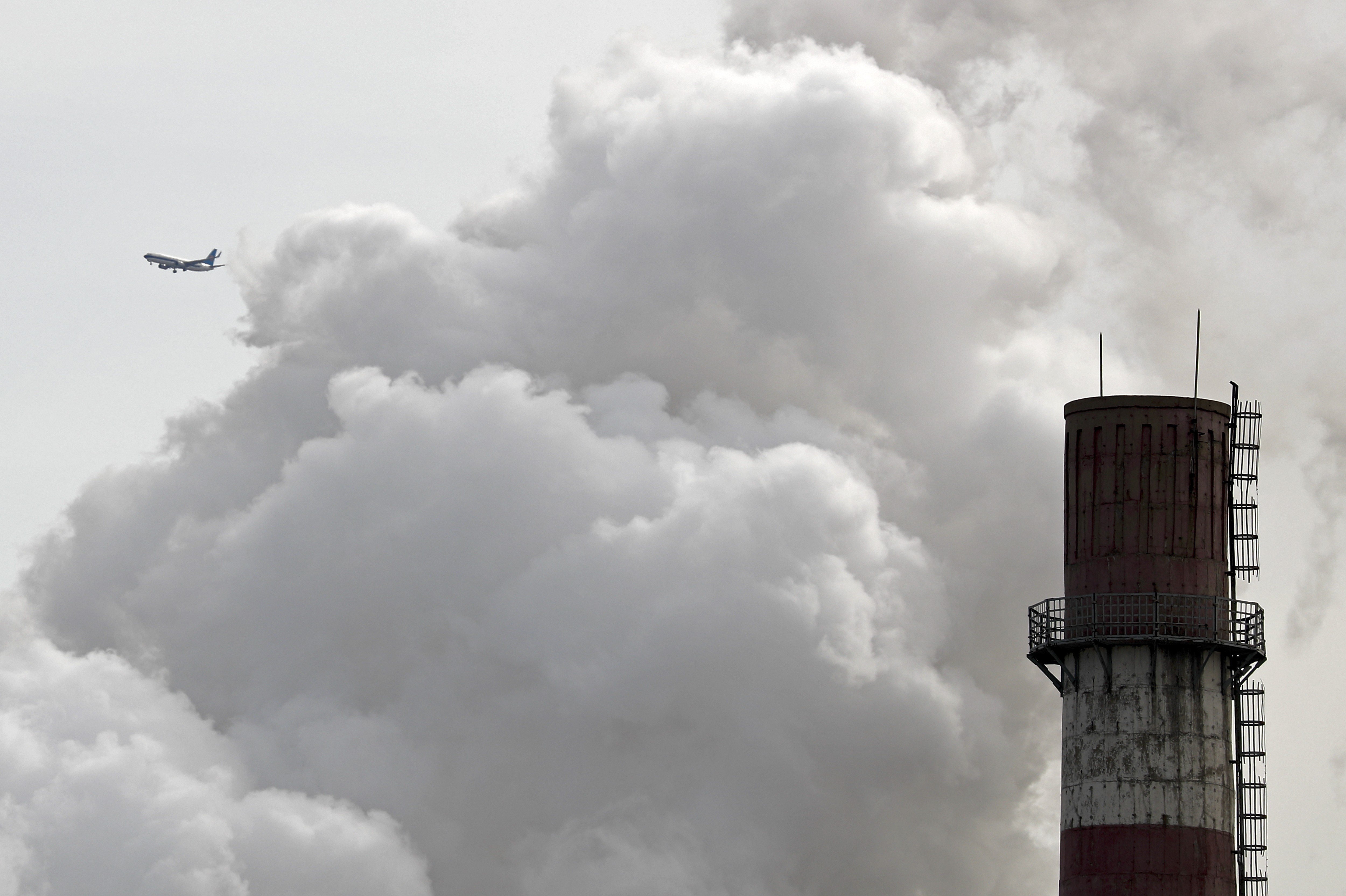 A passenger airliner flies past smoke emitted from a coal-fired power plant in Beijing in 2017. Photo: AP