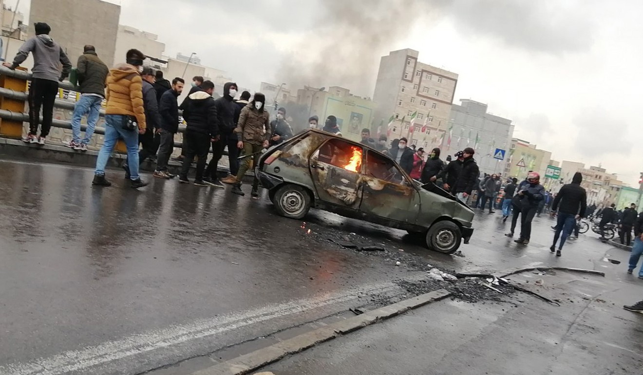 Iranian protesters stand around a burning car in Tehran, Iran, on Saturday. Photo: EPA-EFE