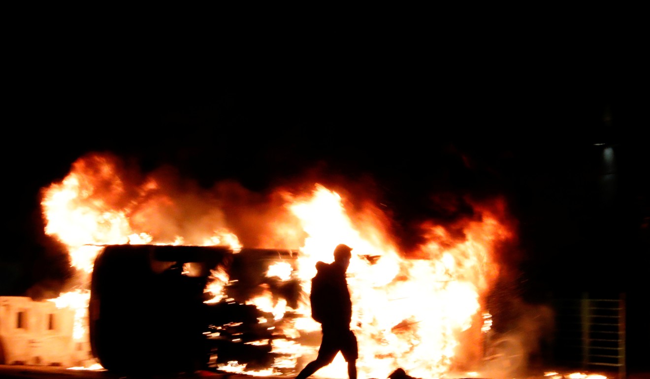 An anti-government protester walks past a burning vehicle in Tseung Kwan O on November 11. Photo: Reuters