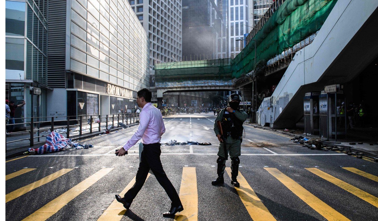 An office worker walks past a policeman after a protest in Central in Hong Kong. Photo: AFP