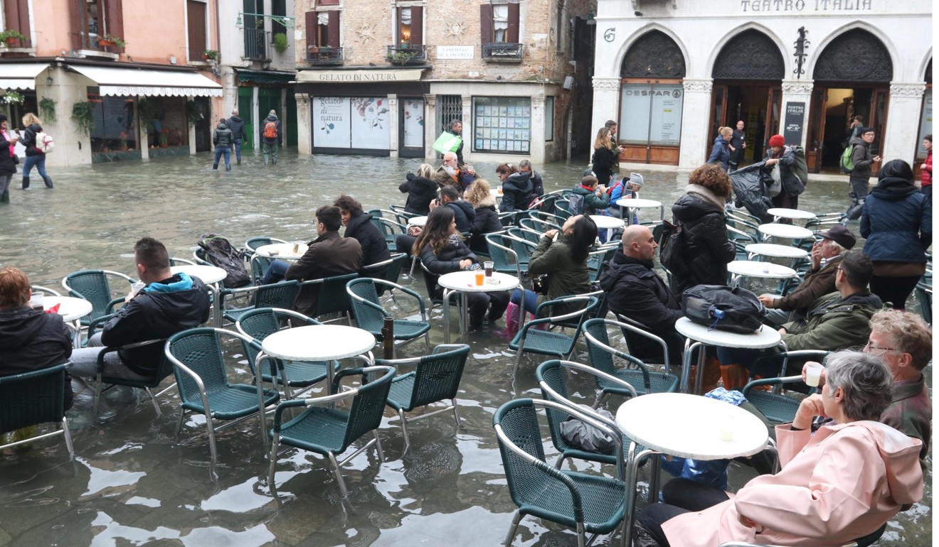 Tourists and residents resume their normal routine despite persistent flooding in Venice. Photo: EPA