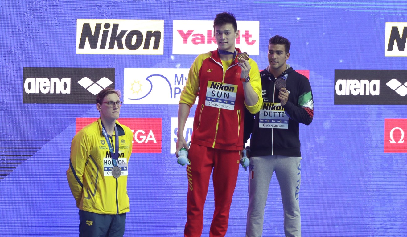 Sun Yang (centre) holds up his gold medal as silver medallist Australia's Mack Horton (left) stands away from the podium. Photo: AP