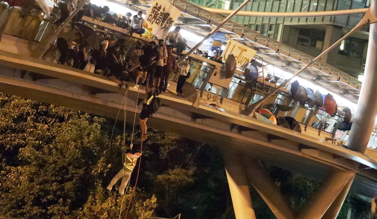 Protesters lower themselves down with ropes from a bridge to a highway at Hong Kong Polytechnic University to escape from police overnight on Monday. Photo: Felix Wong