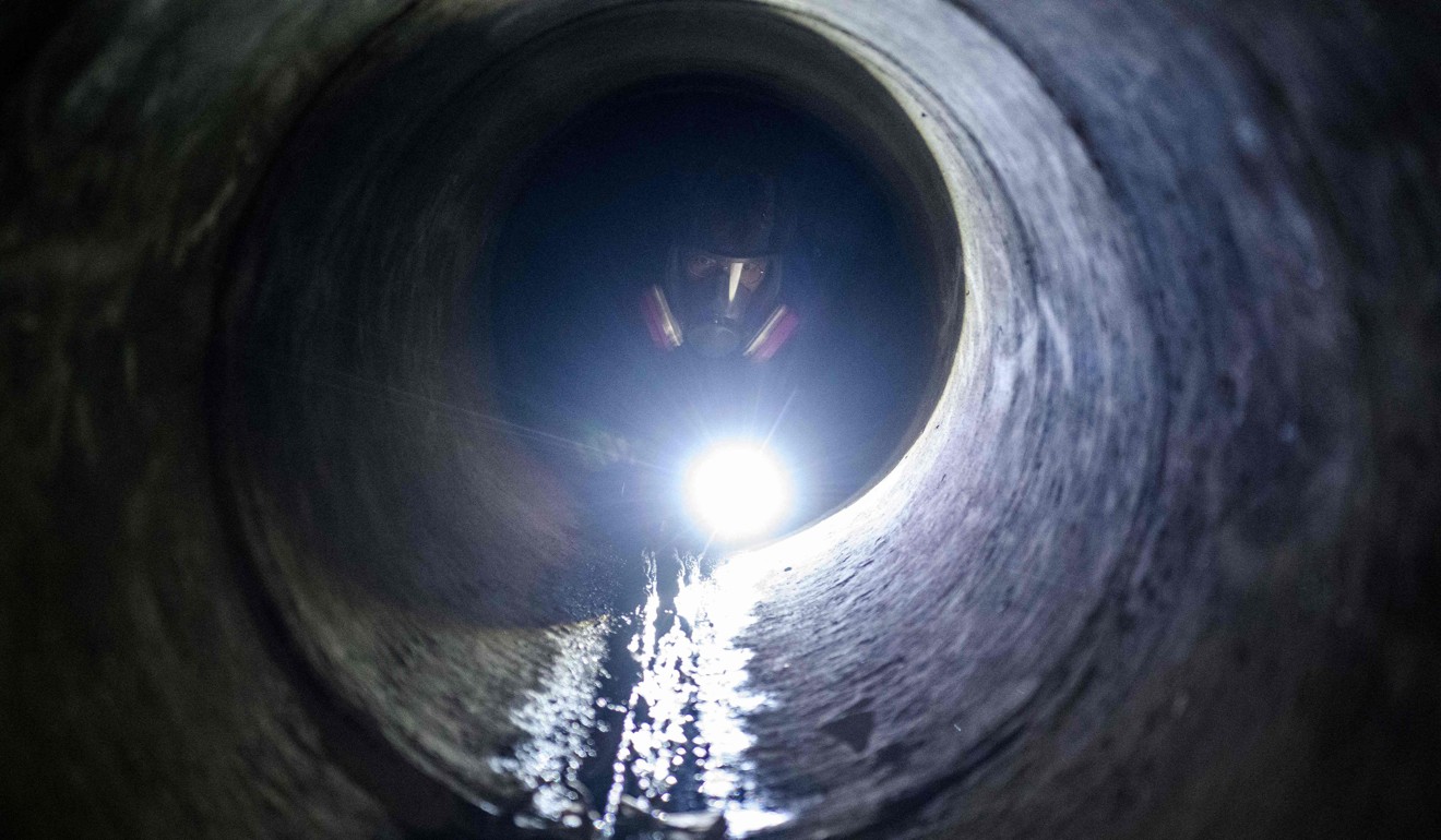 A protester crawls down a tunnel after dropping down a manhole. Photo: AFP
