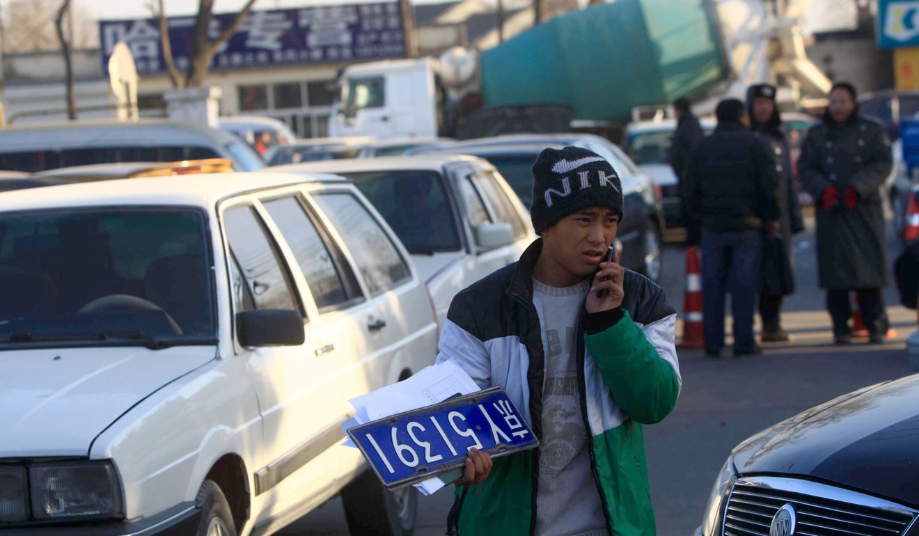 A man carries a number plate at a used car market in Beijing. Photo: AFP