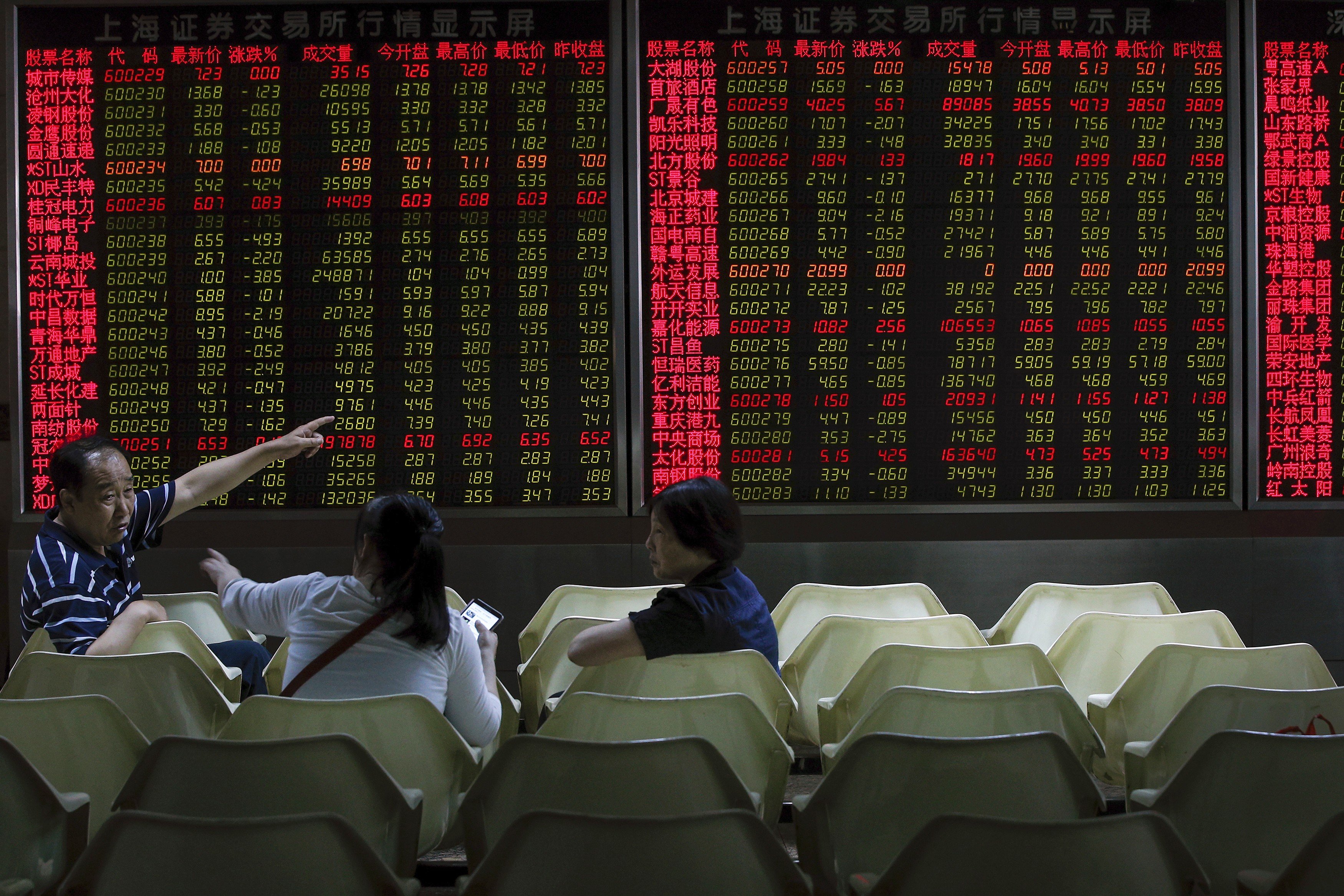 Investors chat as they monitor stock prices at a brokerage house in Beijing. Photo: AP Photo