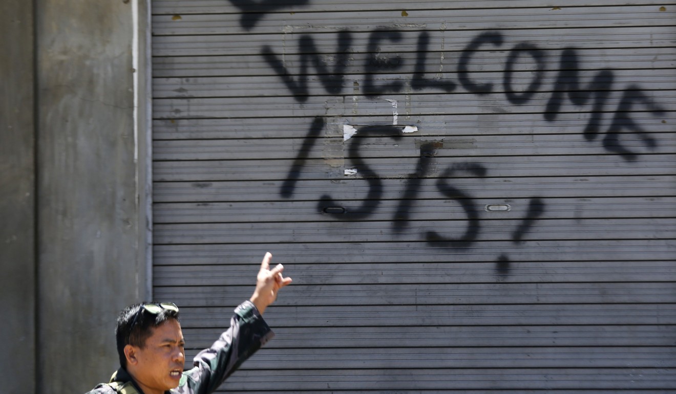 A Filipino soldier gestures towards pro-Isis graffiti in the southern Philippines in 2017. Photo: EPA
