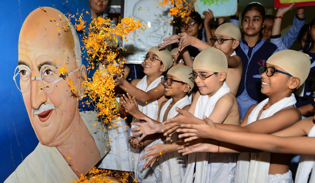 Schoolchildren in Amritsar, India, dressed as Gandhi throw flowers at the independence leader’s portrait on October 1, during an event marking the eve of the 150th anniversary of his birth. Photo: AFP