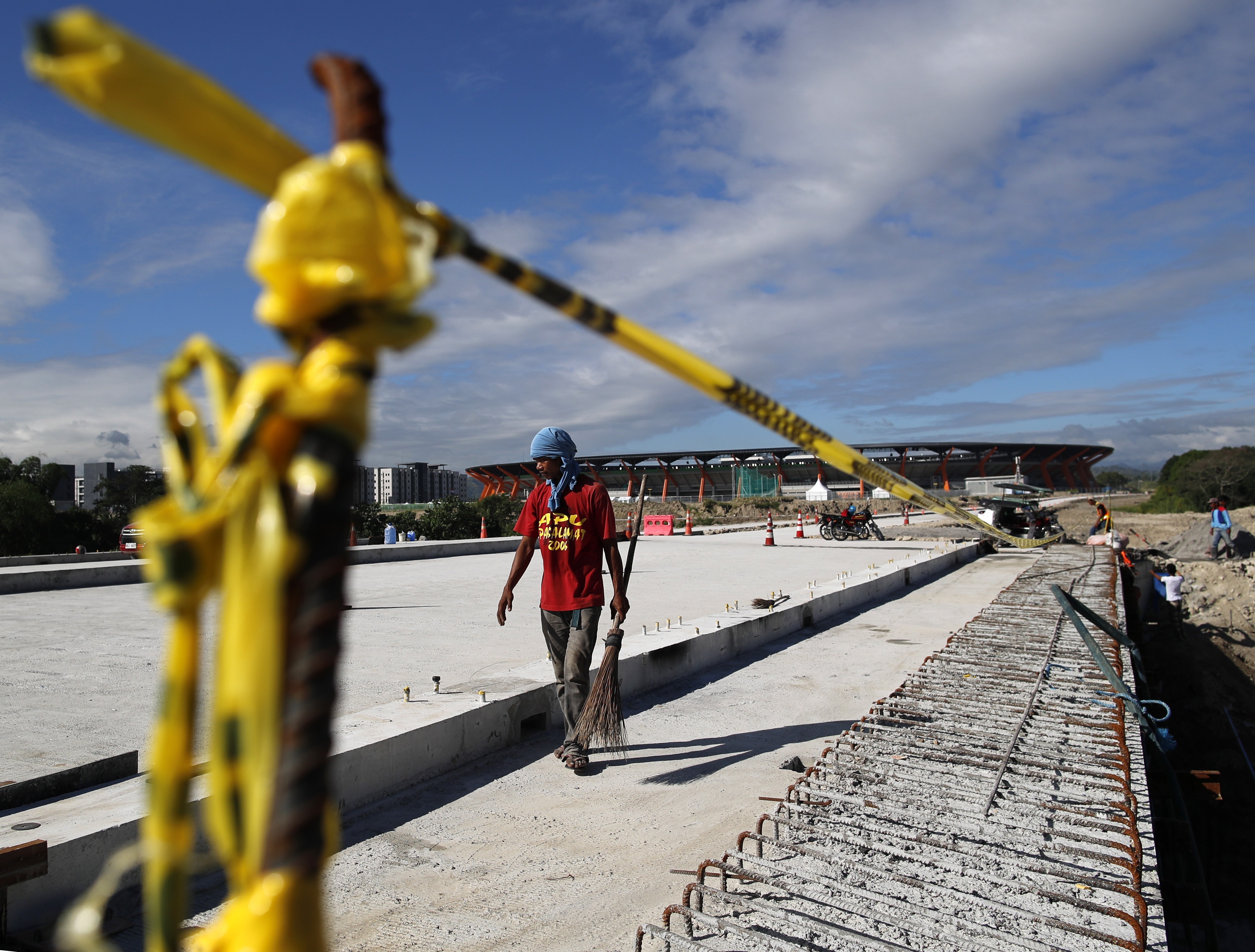 A Filipino worker walks along an unfinished road leading to the aquatics centre to be used in the SEA Games. Photo: EPA
