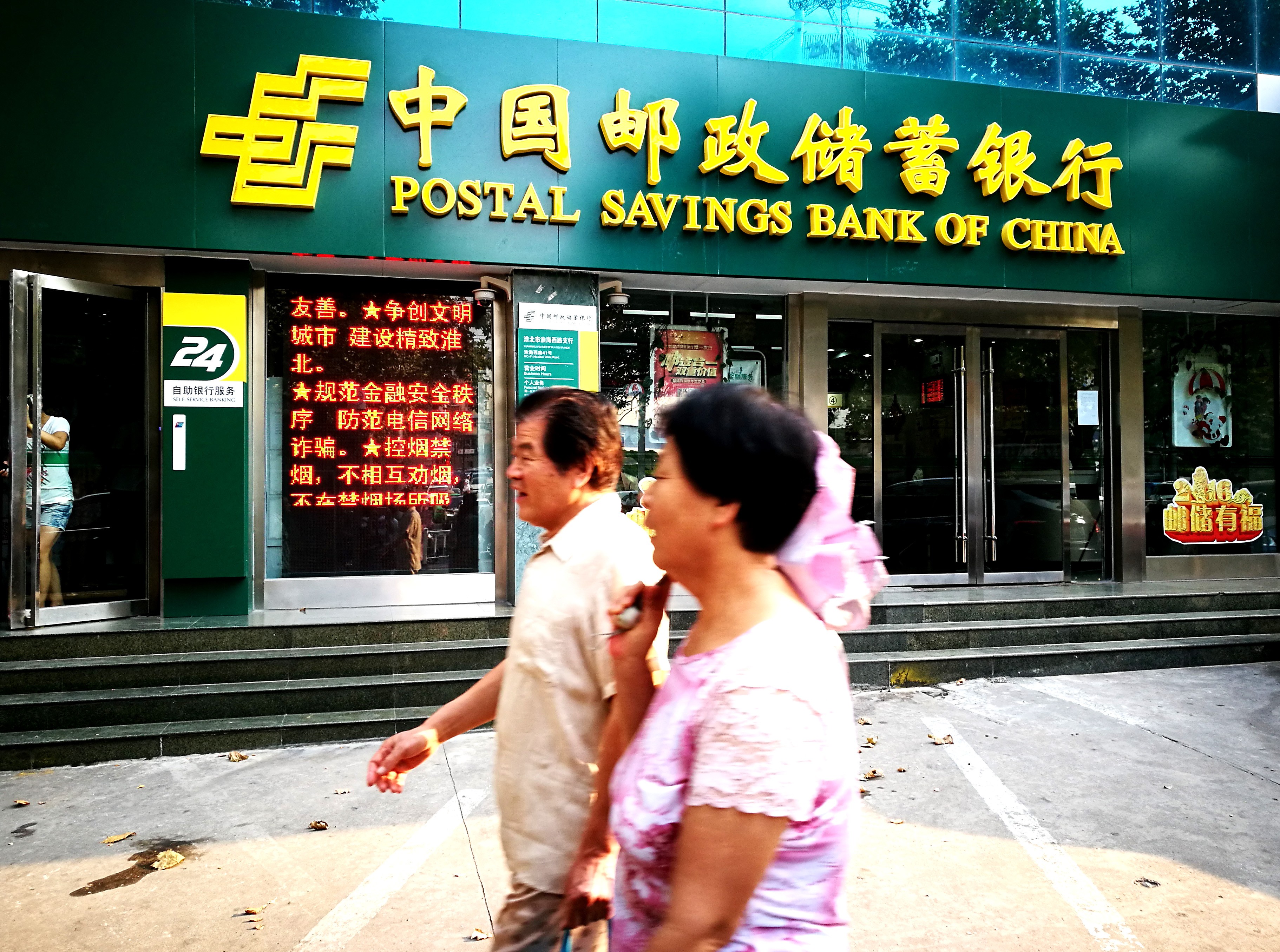 Pedestrians walk past a branch of Postal Saving Bank of China in Huaibei city, in China’s Anhui province. Photo: Imaginechina