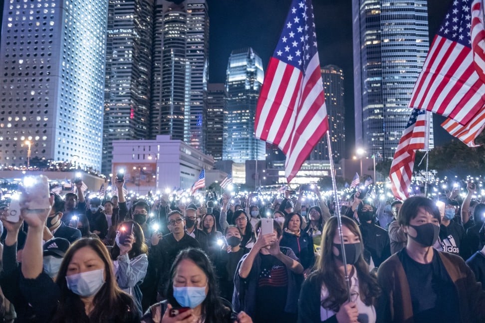 デモ参加者は、11月28日に香港で開催された「香港人権および民主主義法のための感謝祭の集会」でアメリカの国旗を振りながら、スマートフォンのライトを照らします。写真：ブルームバーグ