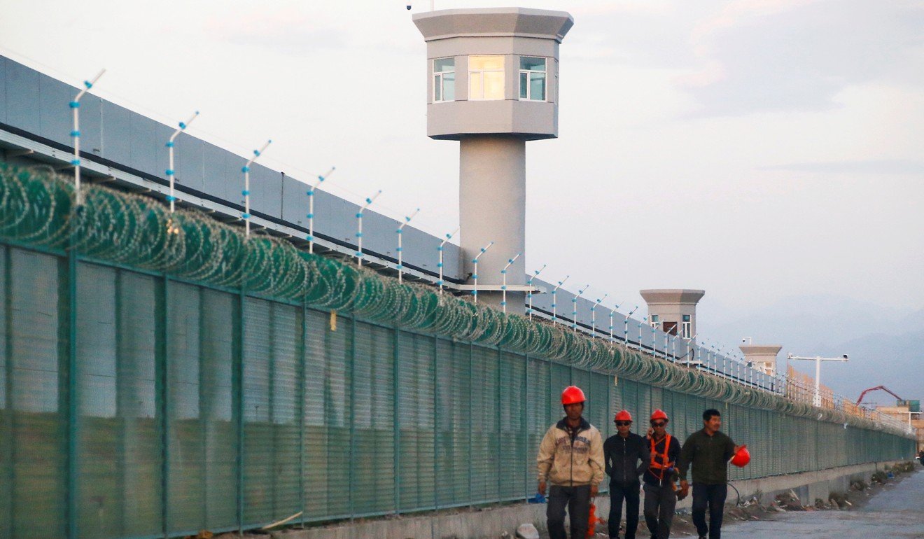 Workers walk by the perimeter fence of what is officially known as a vocational skills education centre in Dabancheng in Xinjiang Uygur autonomous region. Photo: Reuters