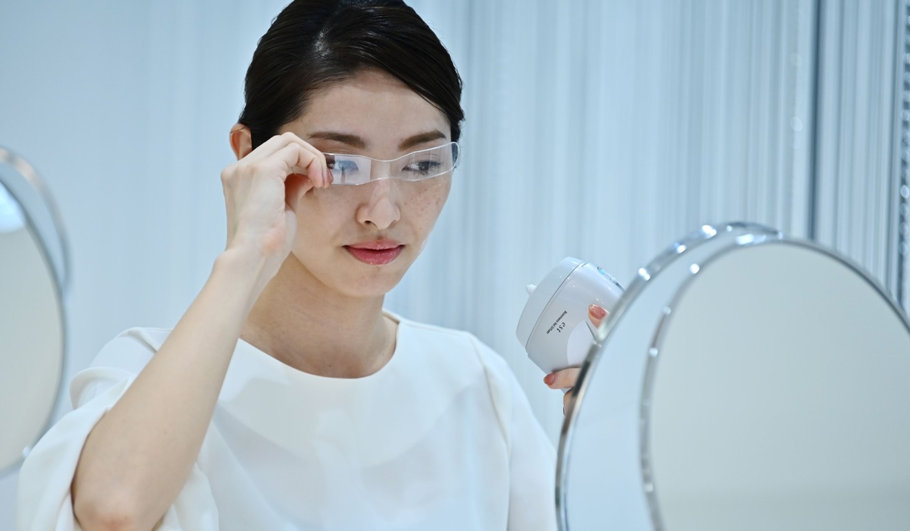 A Kao employee uses a palm-sized diffuser on her face, during a product demonstration in Tokyo. Photo: AFP