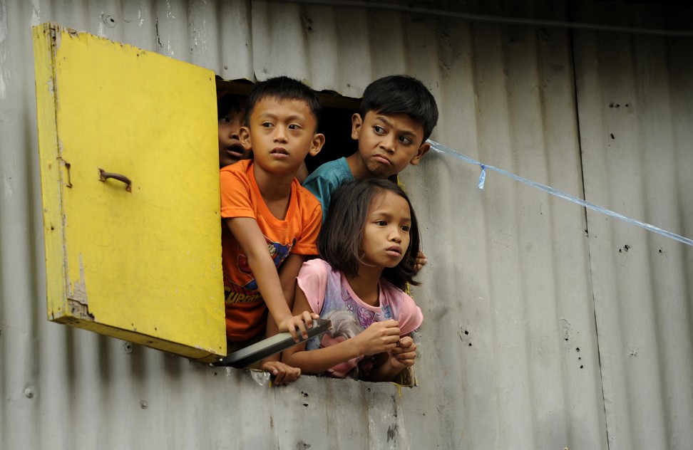 Young residents look out of a window of a shantytown in Manila. Many challenges remain for Asia, including combating poverty. Photo: AFP