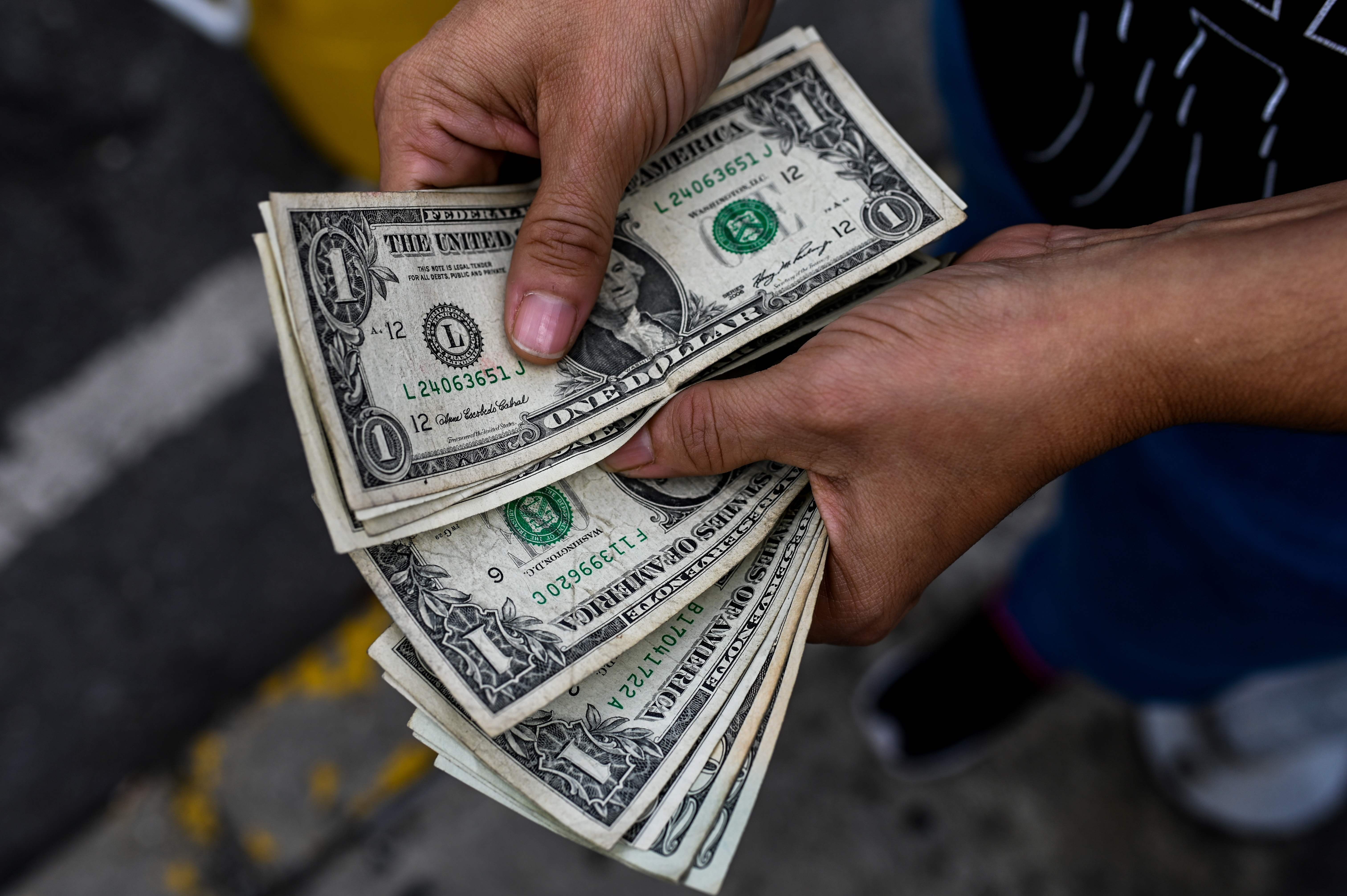A street hawker counts dollar bills in Caracas, Venezuela, on November 19. In Venezuela, the US dollar is used for most transactions after years of hyperinflation and devaluation of the bolívar. Photo: AFP