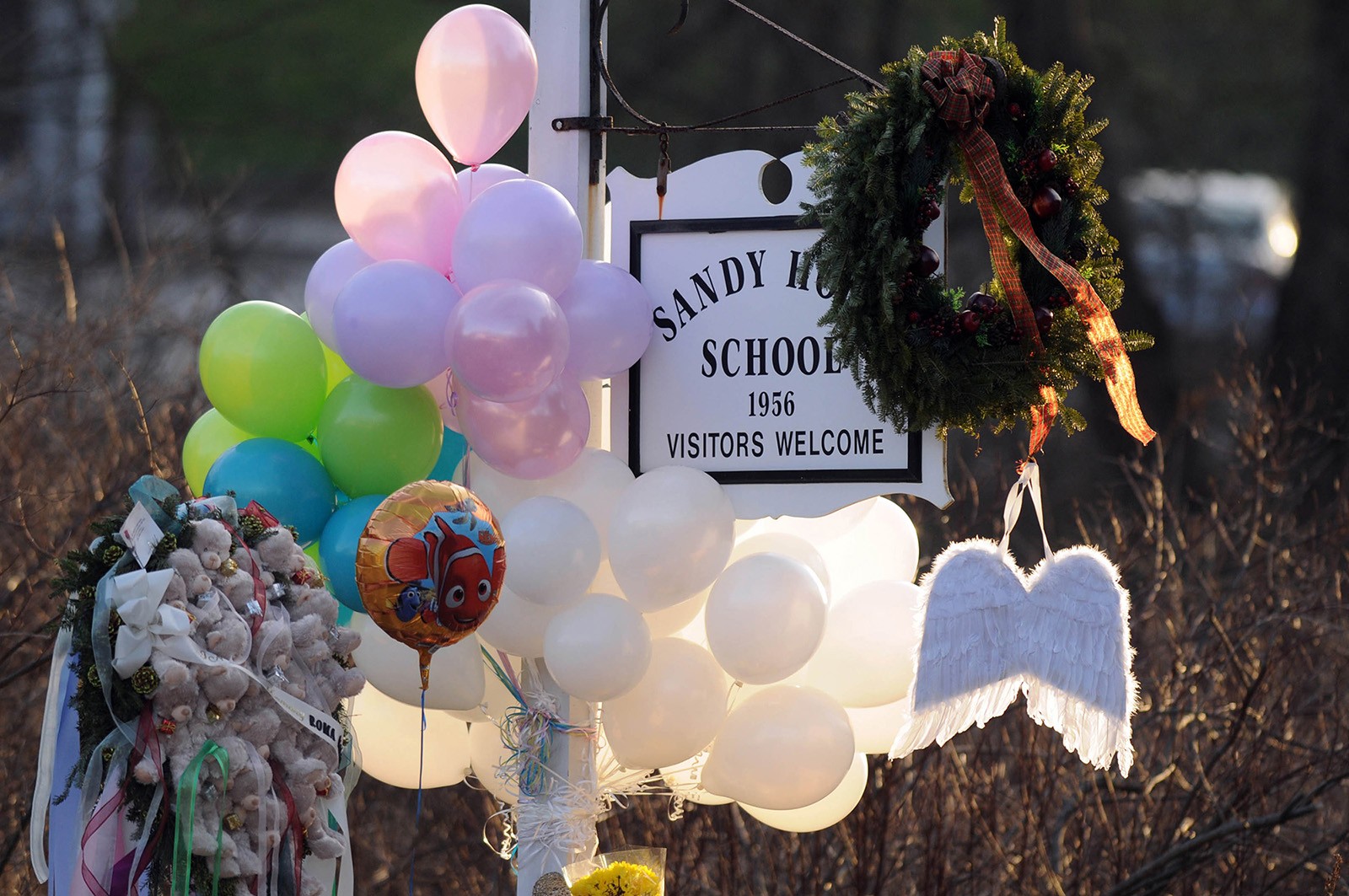 Flowers, teddy bears, candles, balloons and a pair of angel wings left by mourners are seen at the Sandy Hook Elementary School sign. Photo: TNS